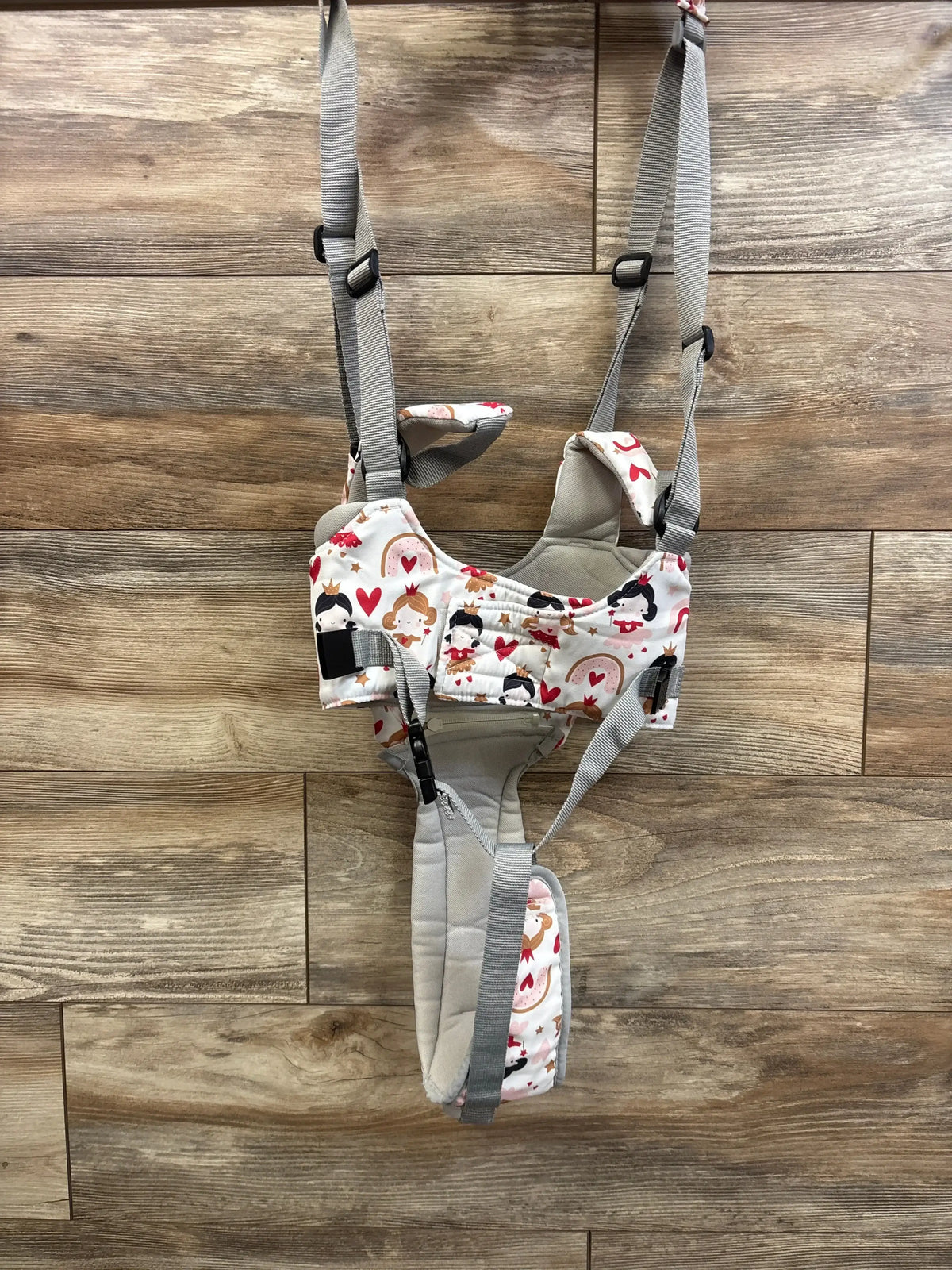 Front view of Watolt baby walking harness in princess print with padded seat and adjustable gray straps on wood background
