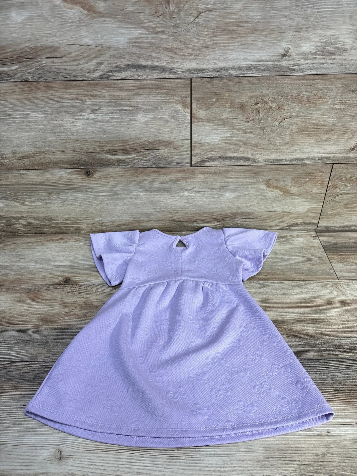 Front view of a purple Hello Kitty jacquard knit dress in size 2T showcasing flutter sleeves and gathered waist on wood flooring