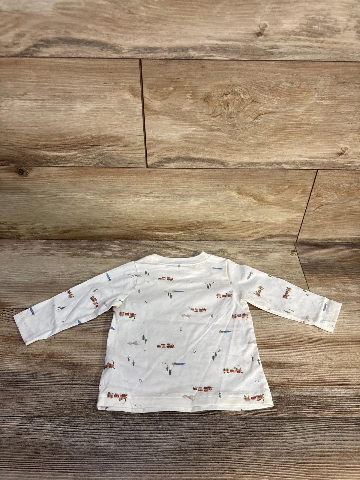 Front view of Just One You long sleeve shirt showcasing white cotton fabric and train print on a wood-look background