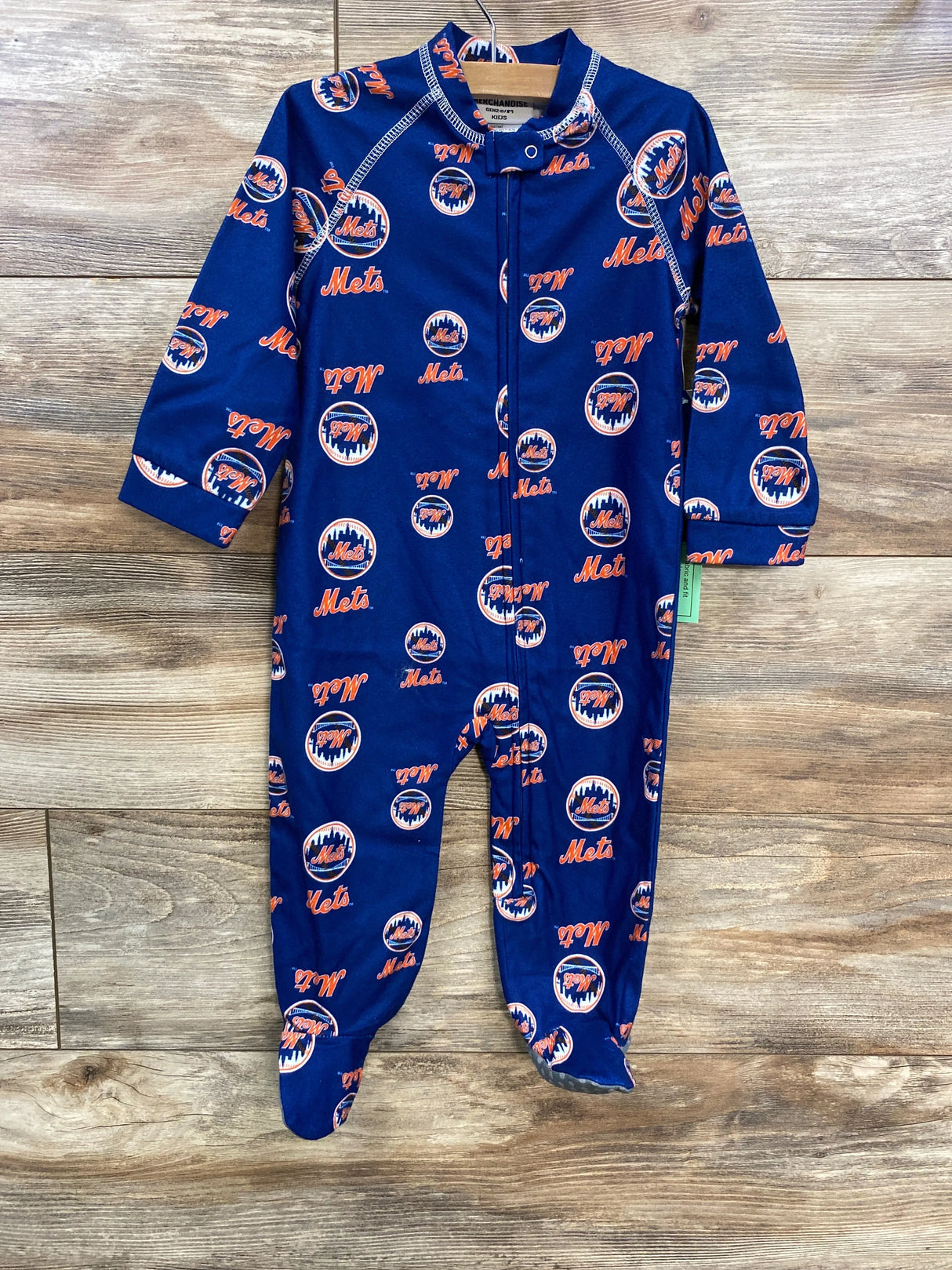 Front view of New York Mets navy zip-up footed onesie showcasing all-over Mets logos and contrast stitching on wood background