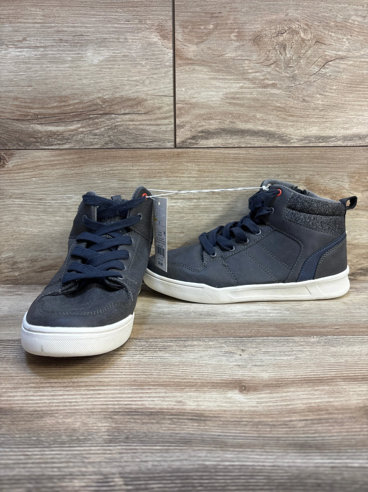 Kids’ navy high-top sneakers with white soles on wood background, gently used shoes