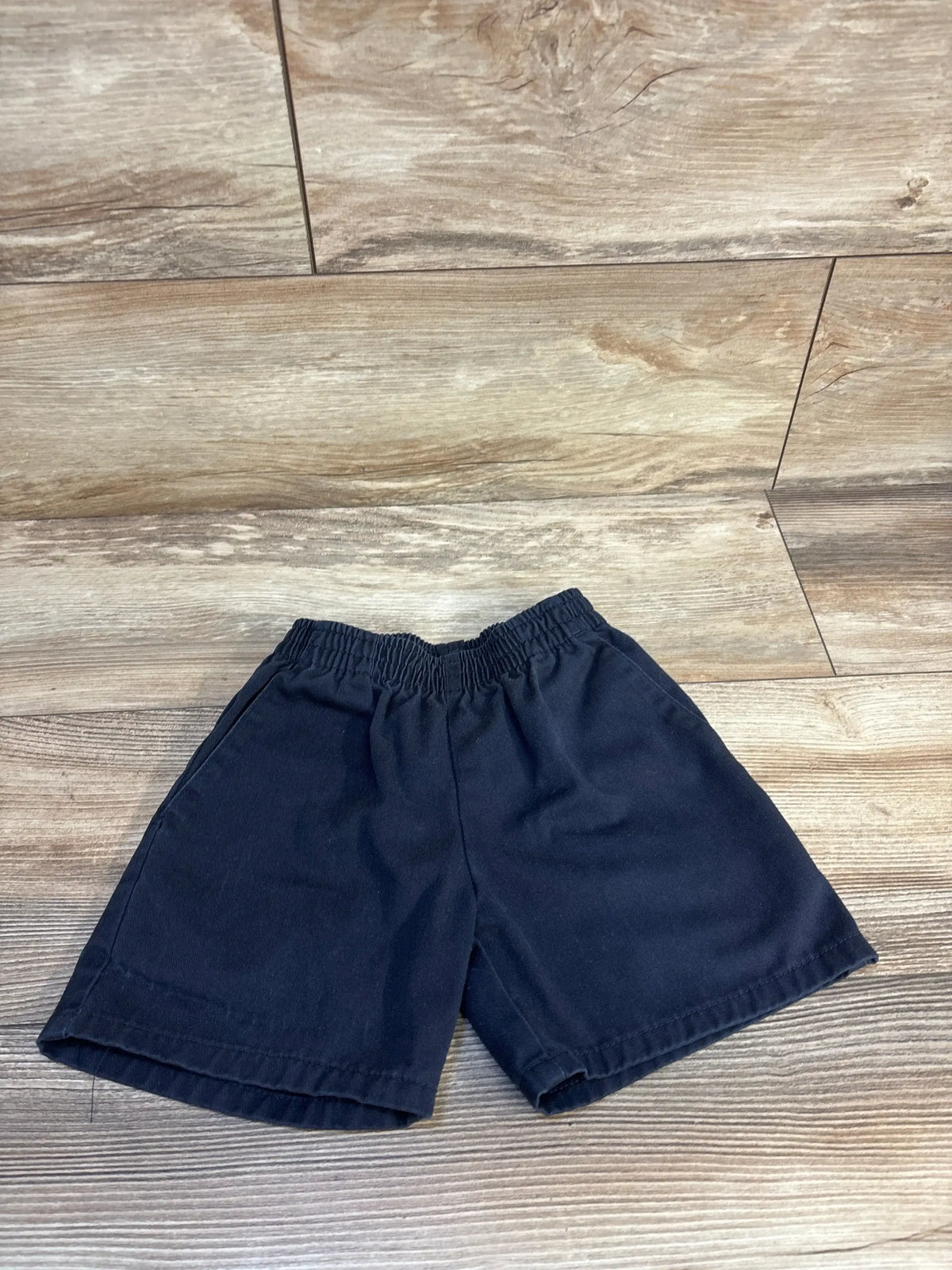 Navy blue kids shorts with elastic waistband on wooden floor