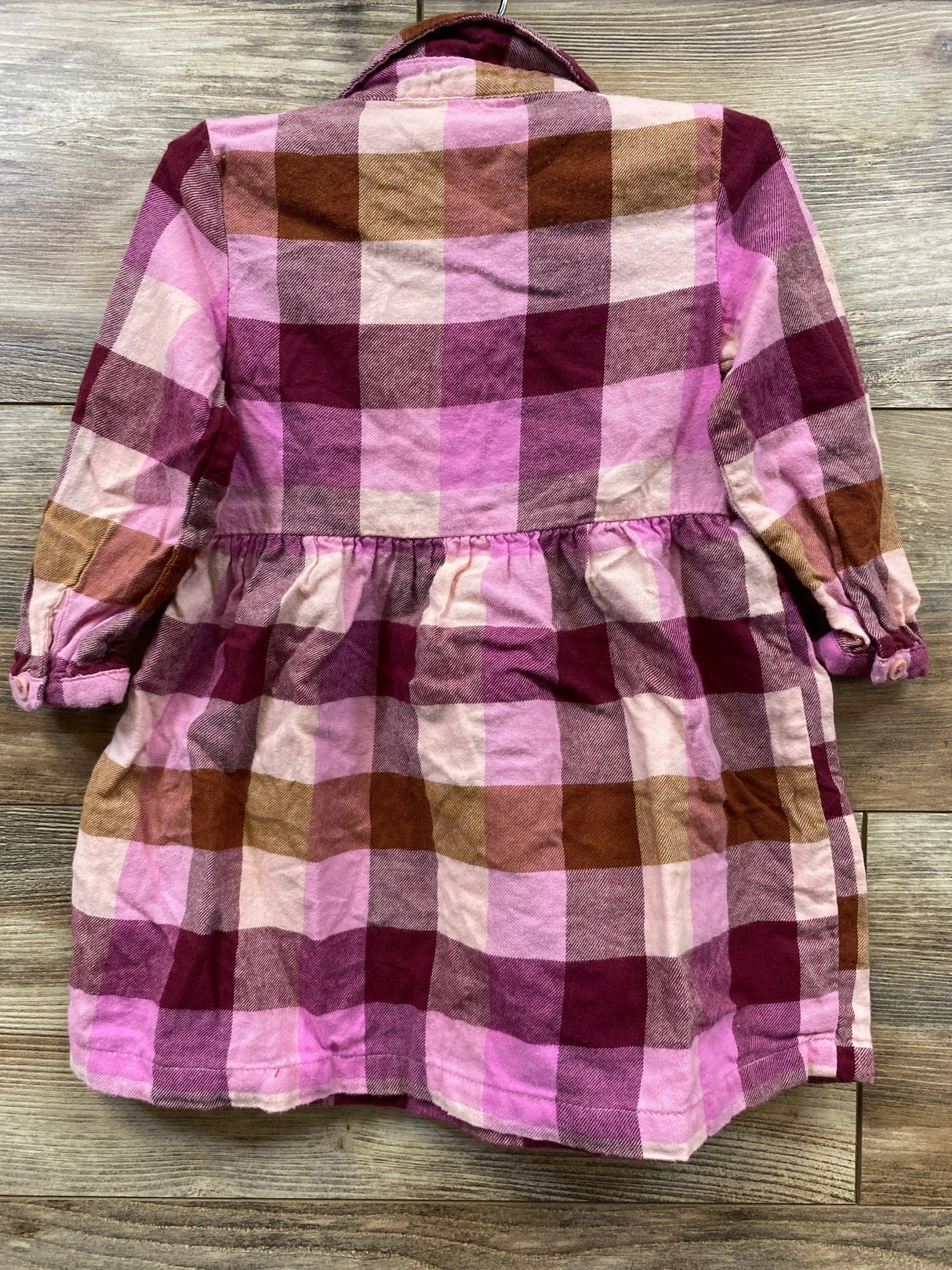 Pink and brown plaid long sleeve girls dress with collar on wood background