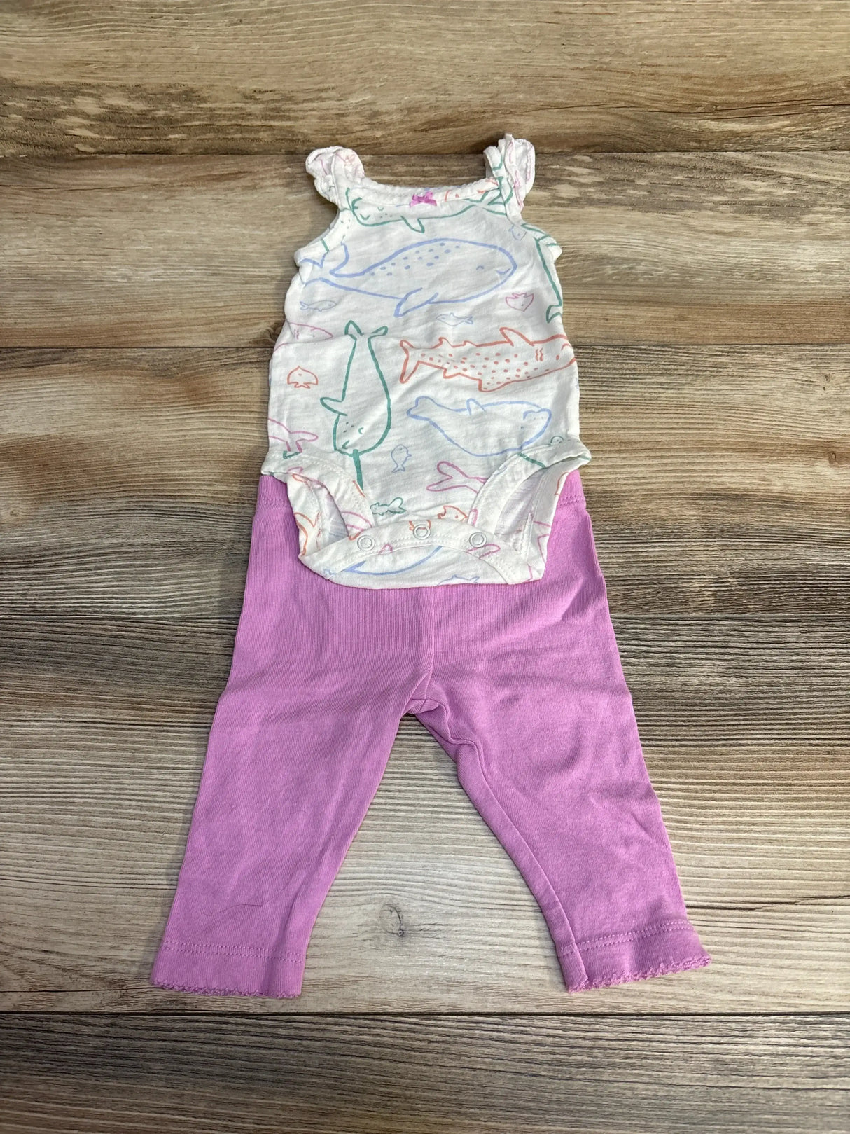 Top-down view of Carter’s 2-piece whale-print bodysuit and pink leggings showcasing a sleeveless bodysuit with snap closures on a wood background, size 3M