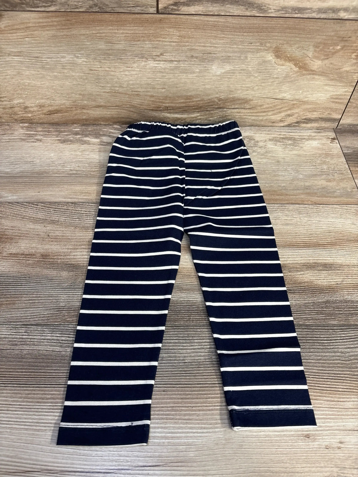 Navy blue and white striped toddler leggings with elastic waist on wood floor