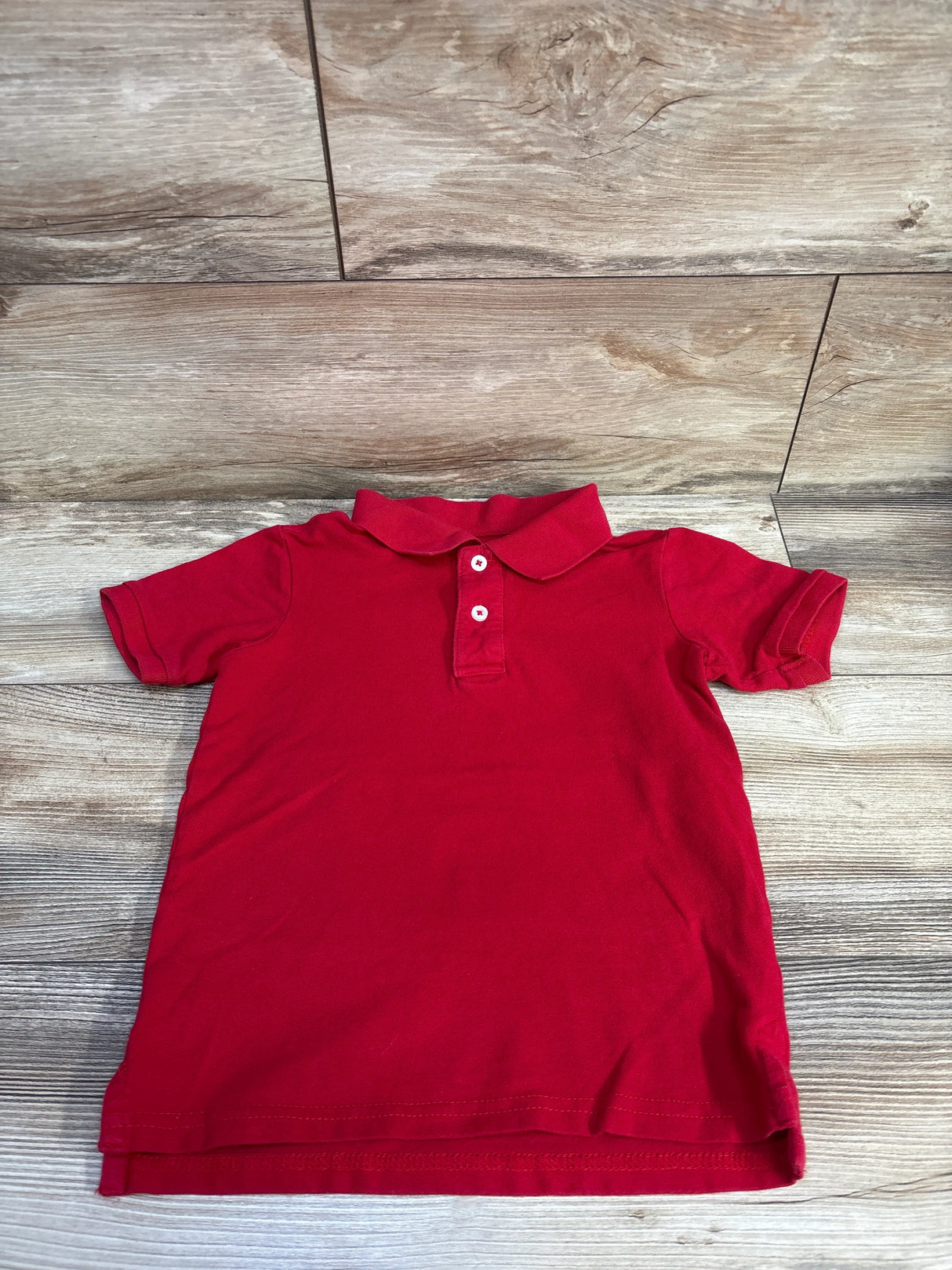 Front view of Wonder Nation red toddler polo shirt (size 4-5T) showing two-button placket and collar on wood floor background