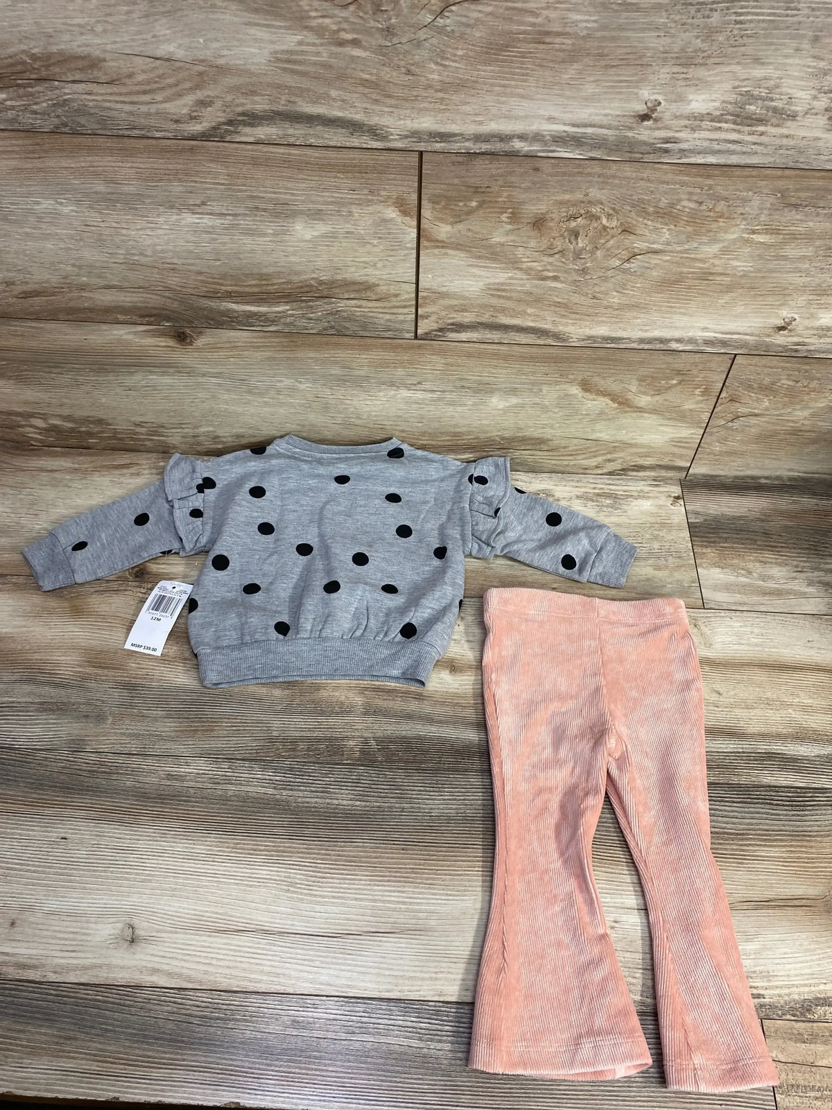 Toddler outfit with grey polka dot sweatshirt and pink corduroy flared pants on wooden floor