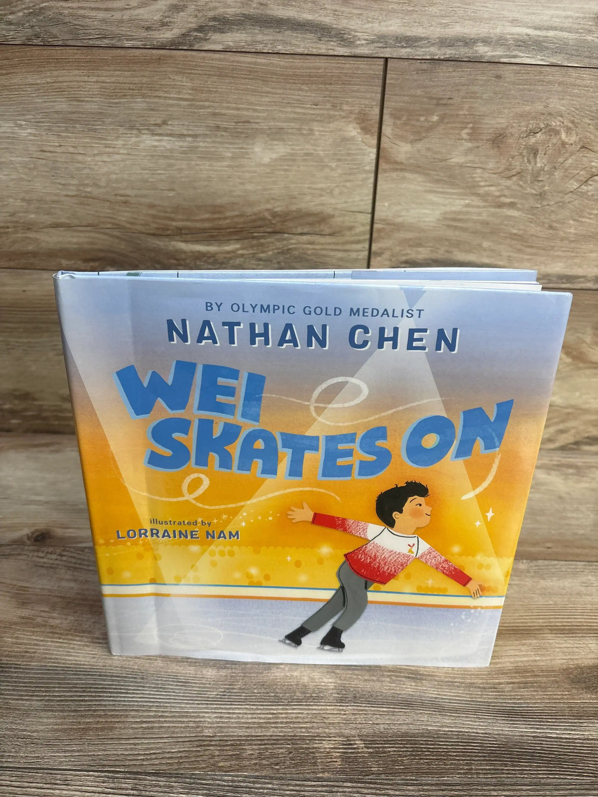 Wei Skates On children's book cover featuring a figure skating boy, wood background