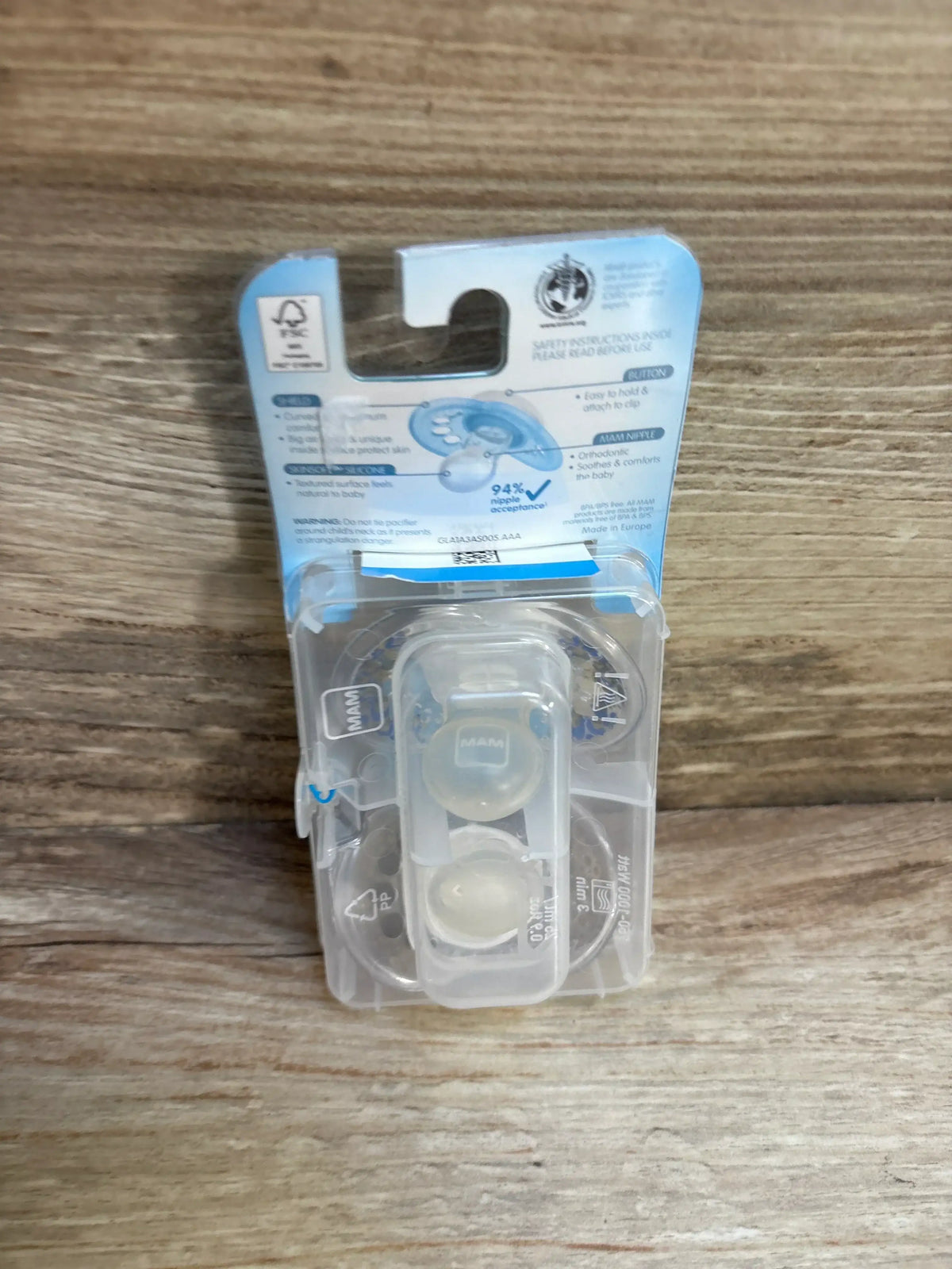 Front view of NEW MAM 2-pack Original clear silicone pacifiers showing included sterilizing travel case and 16m+ label on wood surface
