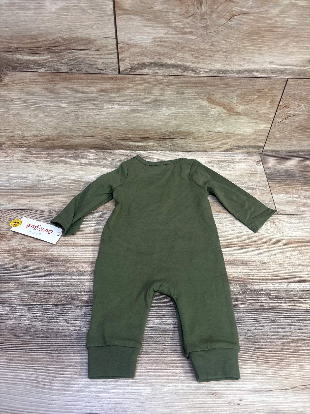 Front view of green Cat and Jack Hello Fall newborn coverall with long sleeves and cuffed legs on a wood-look floor