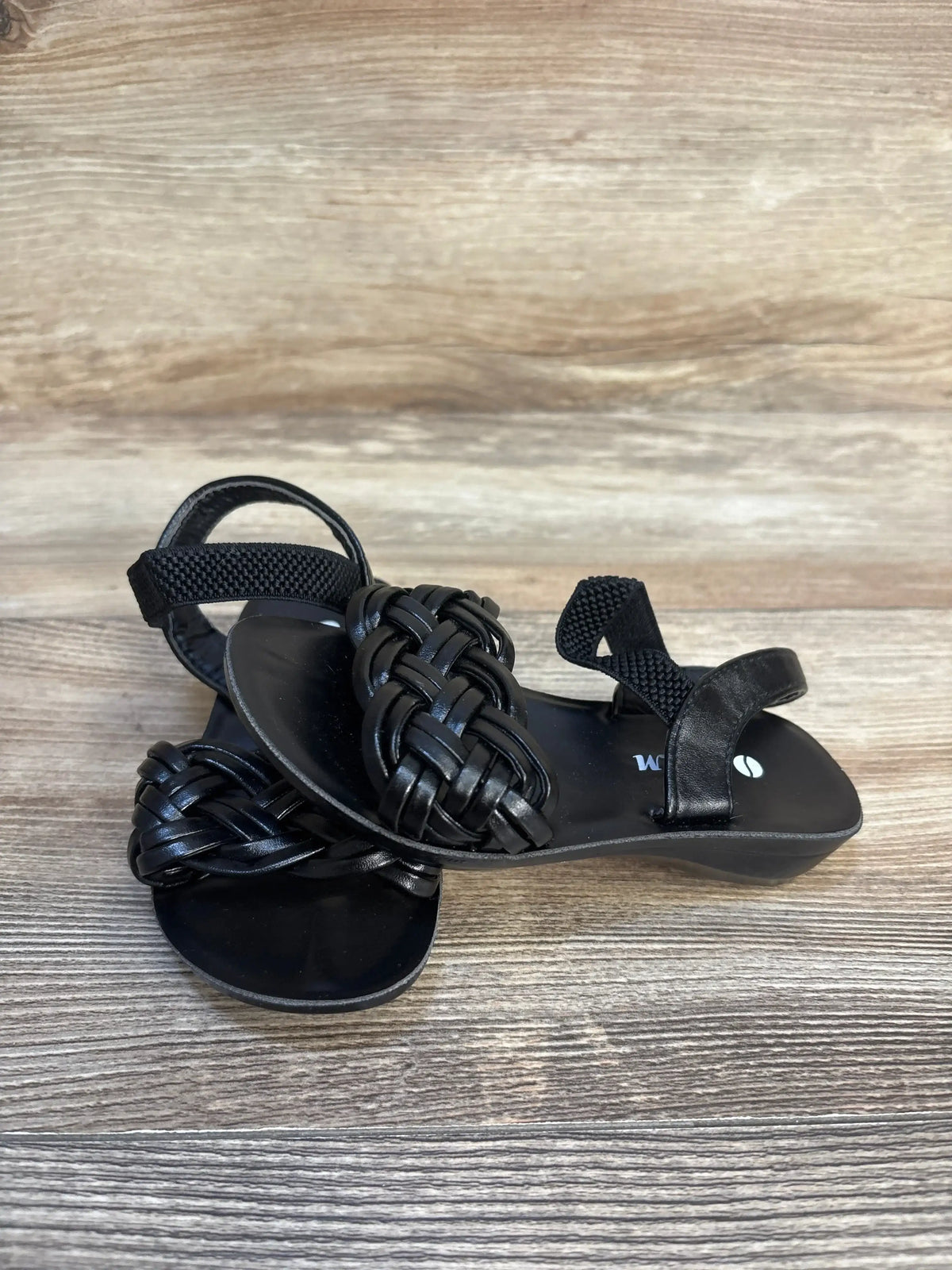 Black woven toddler sandals with ankle strap on wood background, gently used kids shoes
