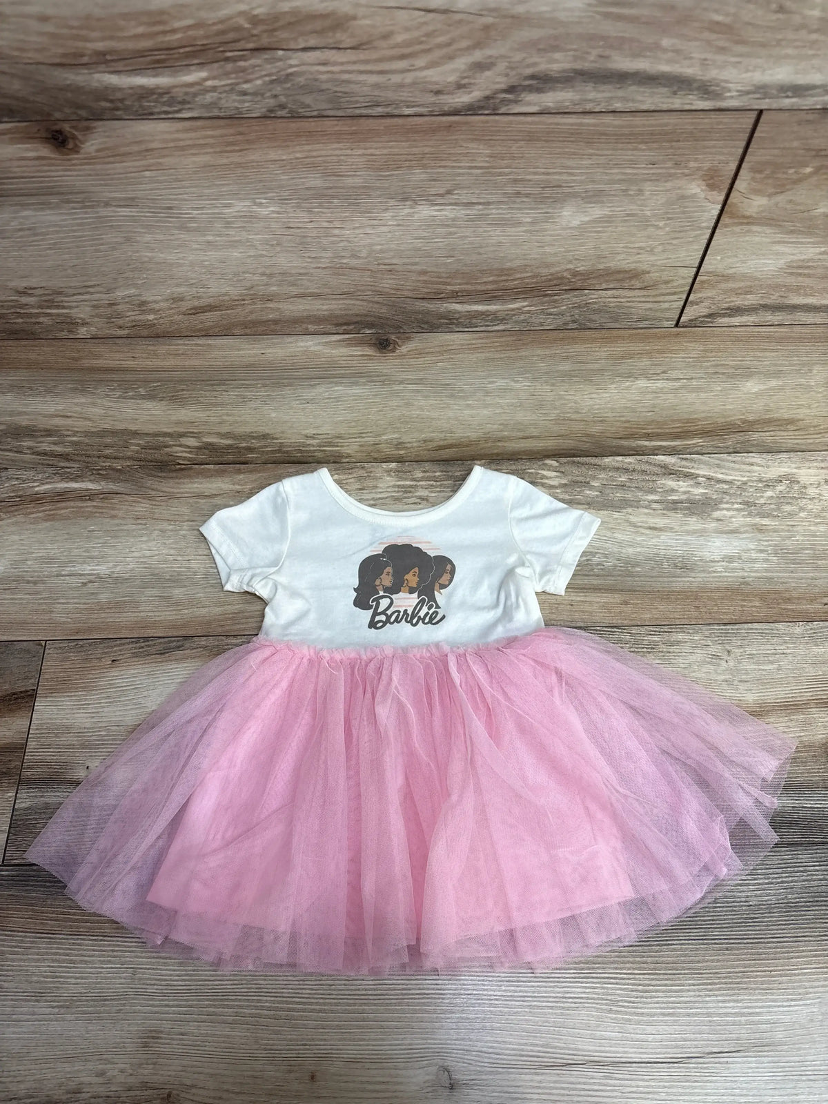White toddler dress with Barbie logo and diverse girl silhouettes on top, pink tulle skirt