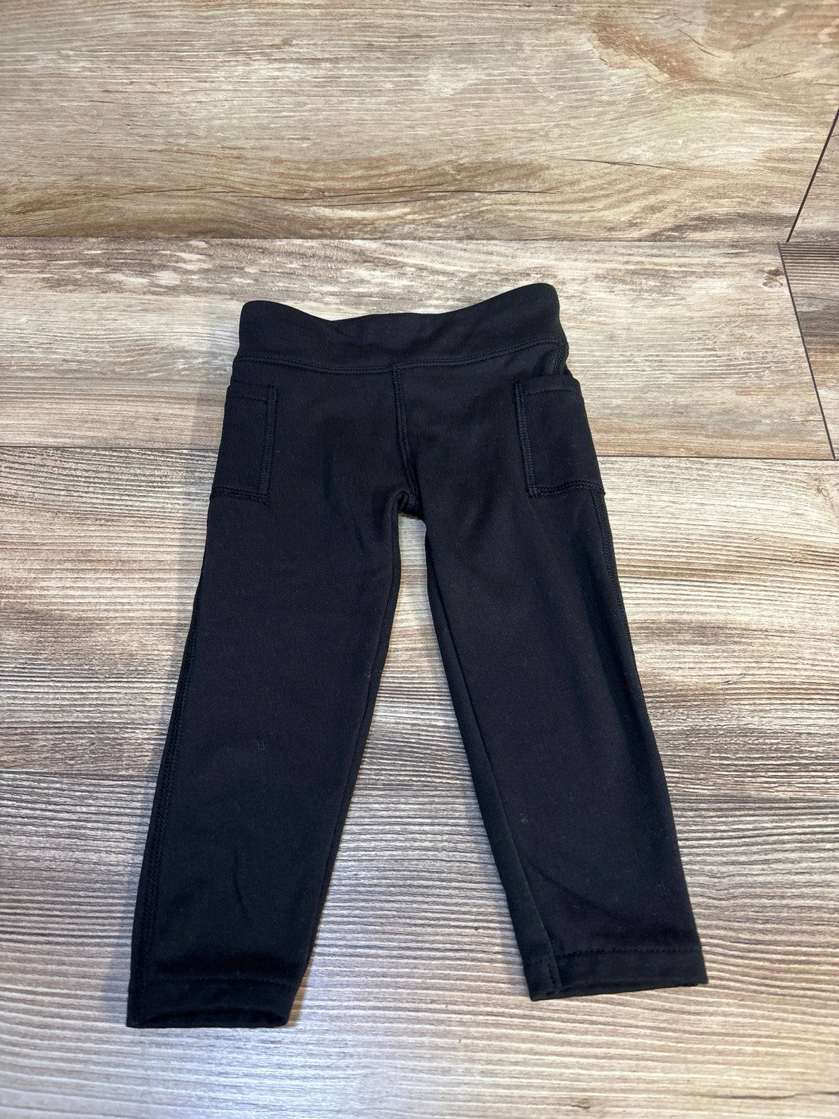 Black toddler leggings with pockets on a wood floor, gently used kids clothing