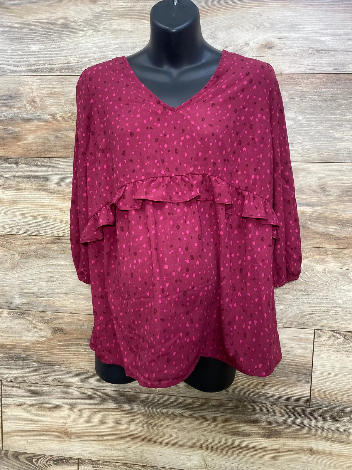 Front view of Isabel maternity ruffle-waist top with V-neck and ruffle waist, berry print on black mannequin