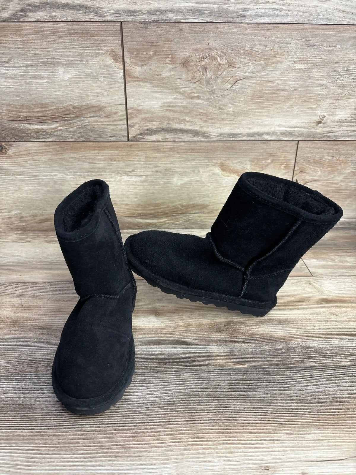 Three-quarter view of Bearpaw Elle Water-Resistant Winter Boots in black sz 1Y showcasing suede upper and treaded rubber sole on wood plank background