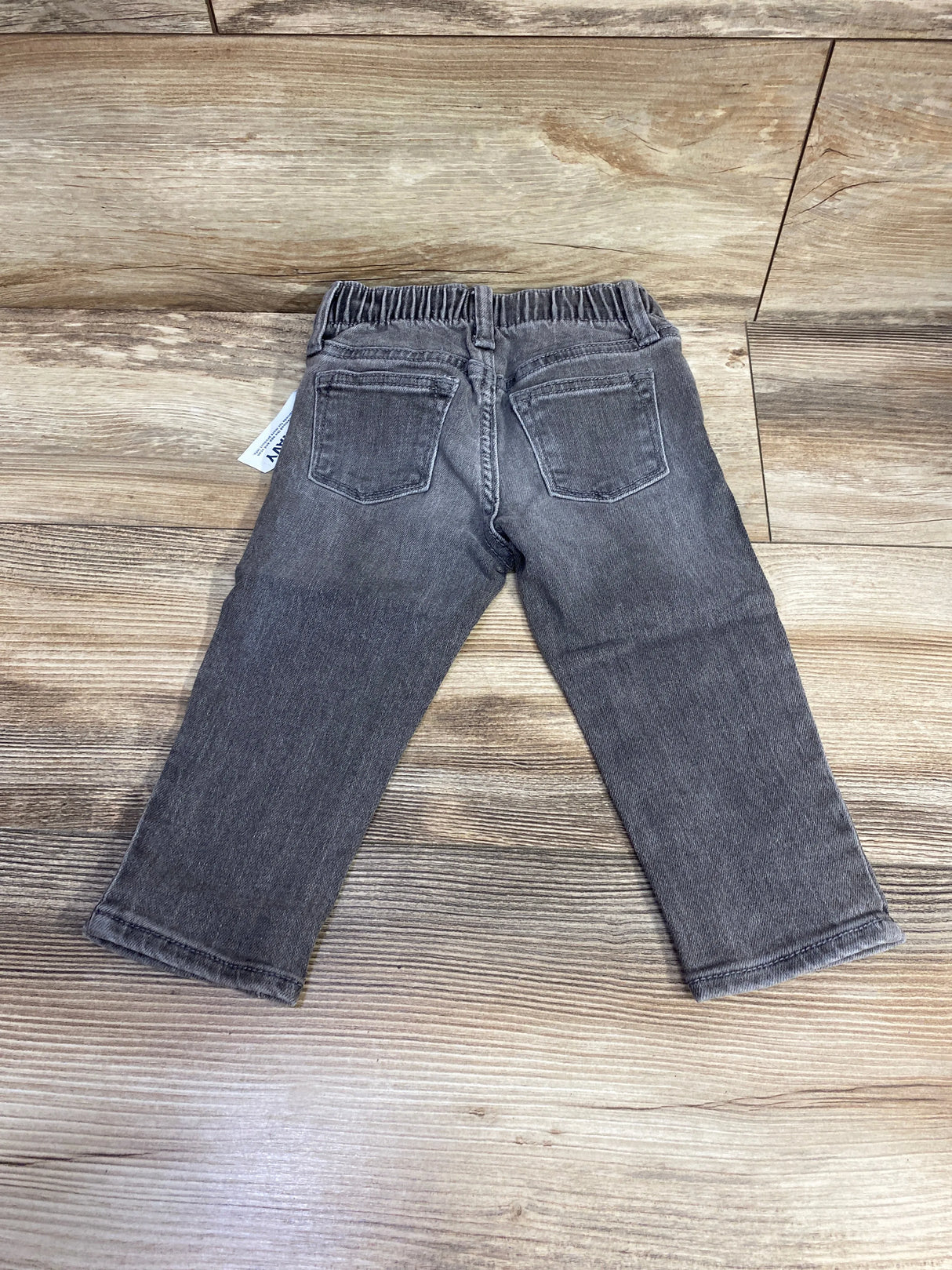 Back view of gray toddler jeans with elastic waist and pockets on wooden floor