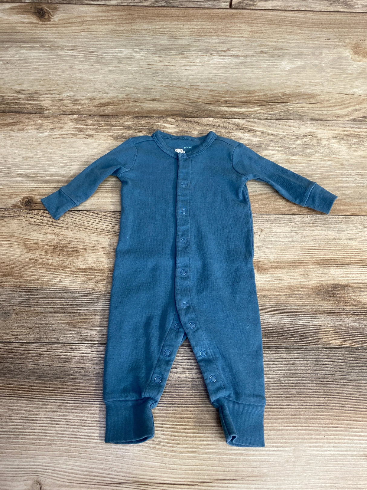 Blue long sleeve baby romper with snaps, laid flat on wooden background