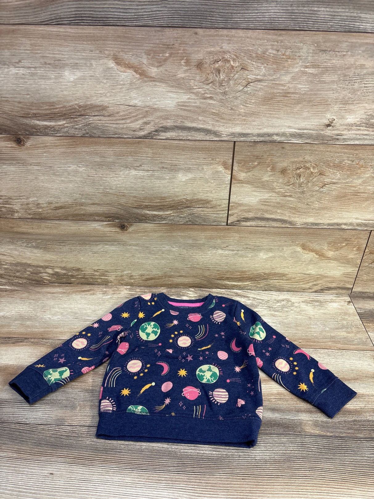 Flat lay of Cat & Jack navy pullover sweatshirt size 2T showcasing colorful planet and space print on wood floor