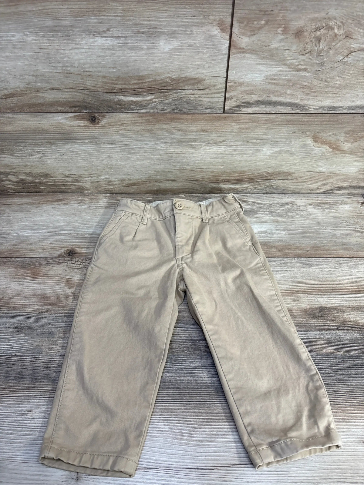 Front flat lay of Baby Gap 2T khaki chinos showing slim fit, button waist and belt loops on wood background