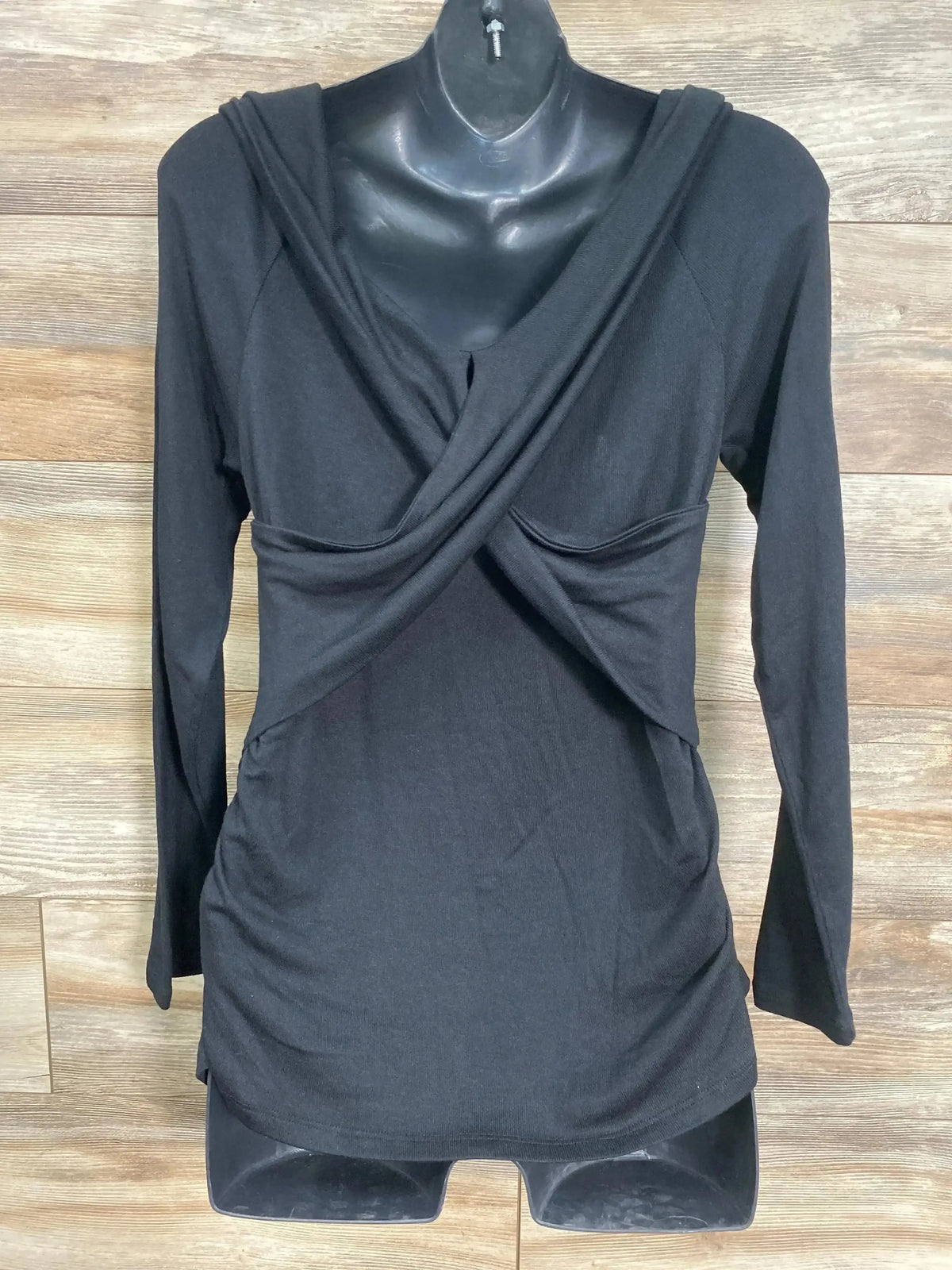 Front view of Isabel maternity crossover nursing top, black, long sleeves, ruched sides, on mannequin against wood background