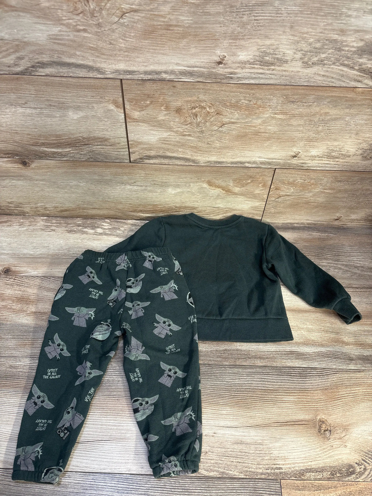 Top-down view of green Star Wars Yoda sweatshirt and joggers set showcasing Yoda-print joggers on a wood floor