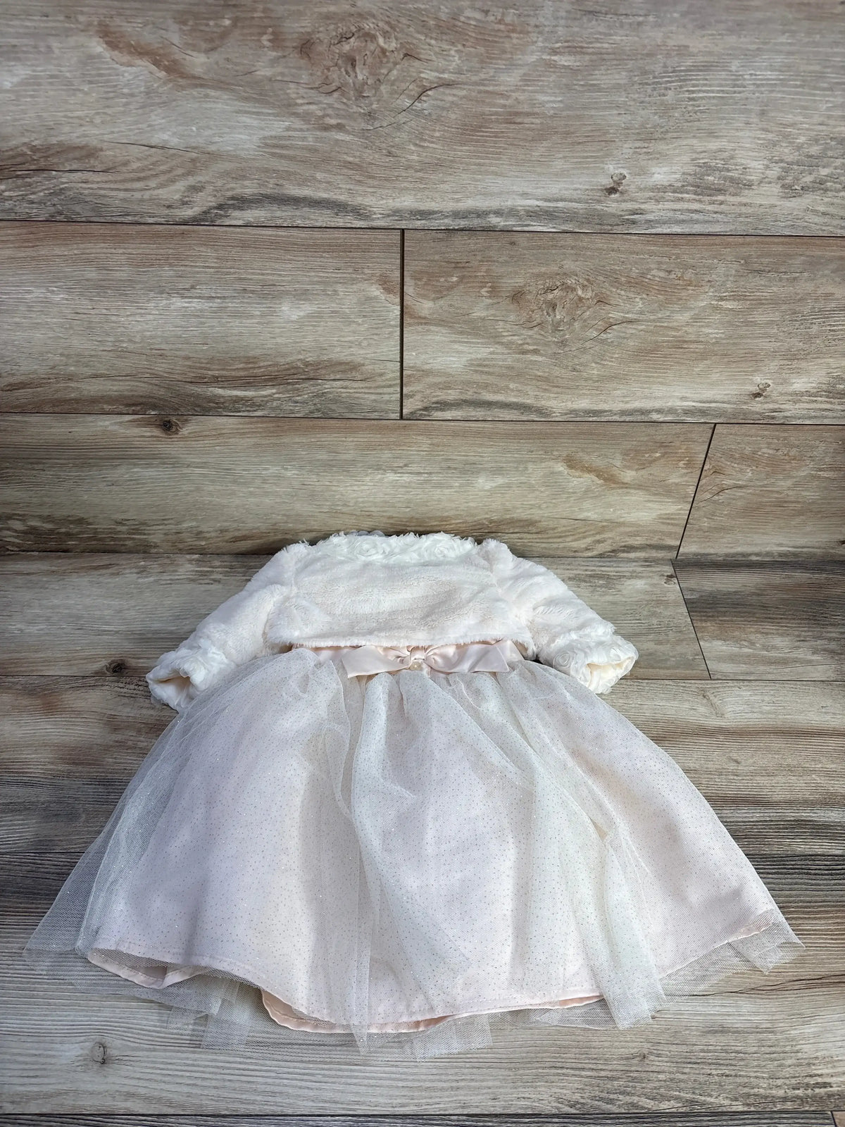 Flat lay of ivory toddler ballerina dress and faux-fur cardigan showing tulle skirt and bow, size 18 months, on light wood background