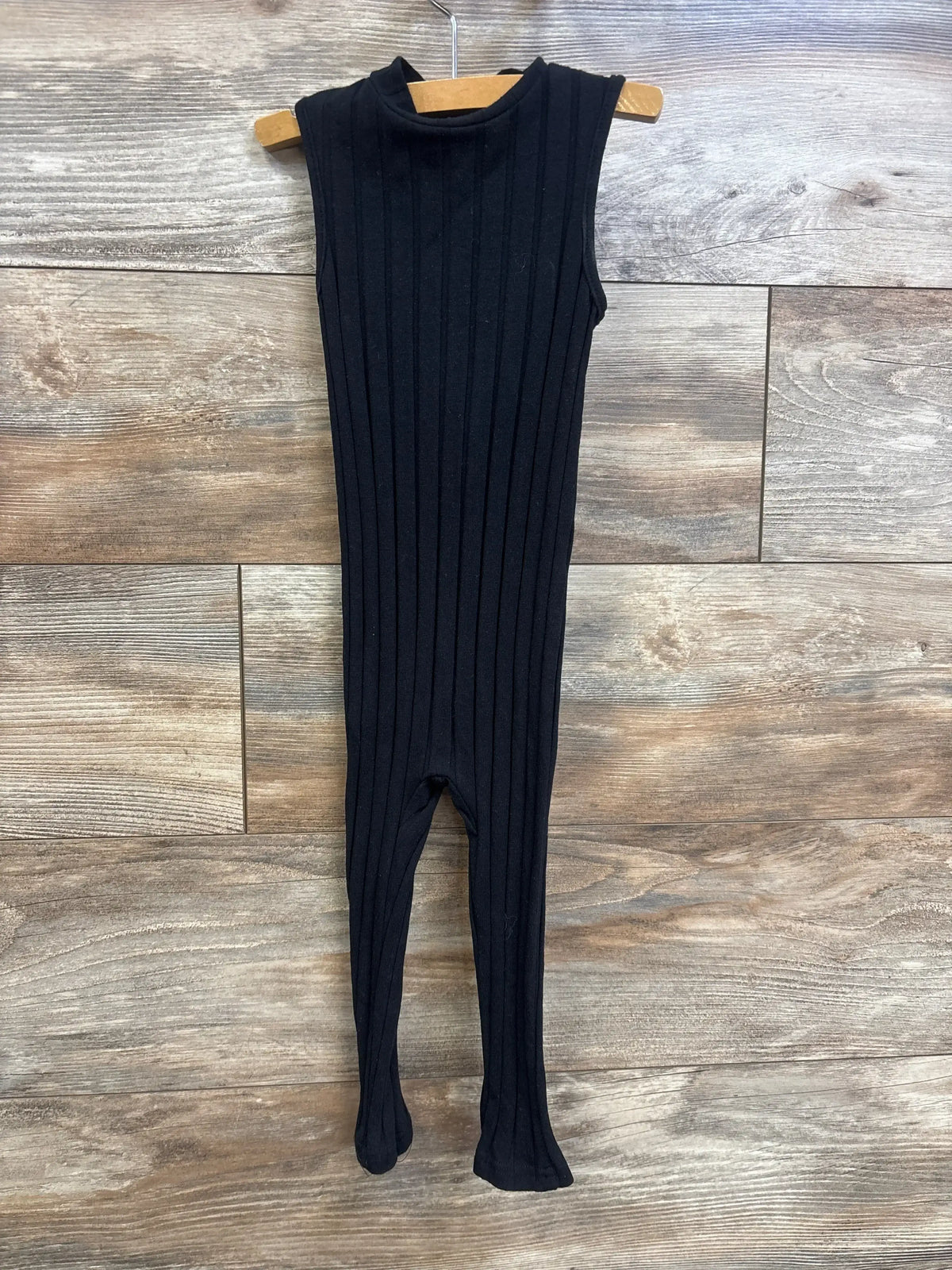 Front view of black ribbed sleeveless jumpsuit, 18-24m, showing mock neck and footed legs on hanger against wood background