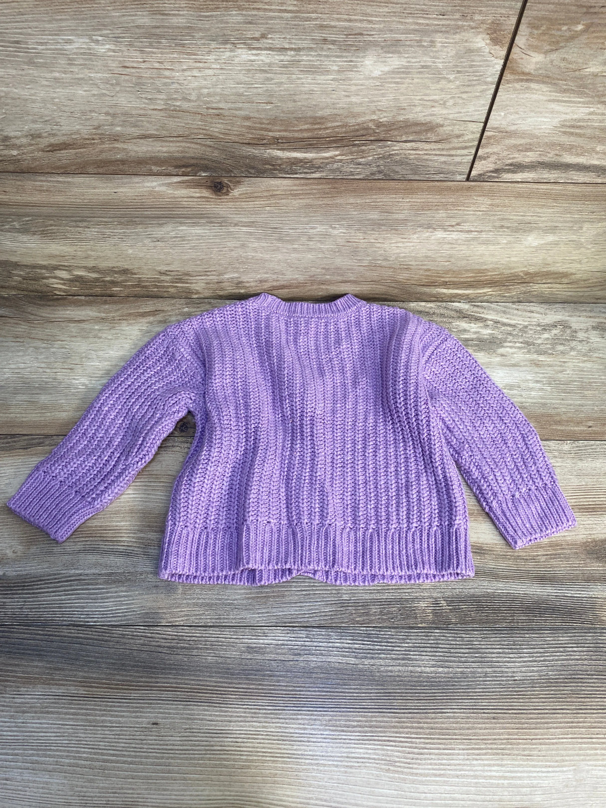 Purple knit toddler sweater with long sleeves on a wooden background