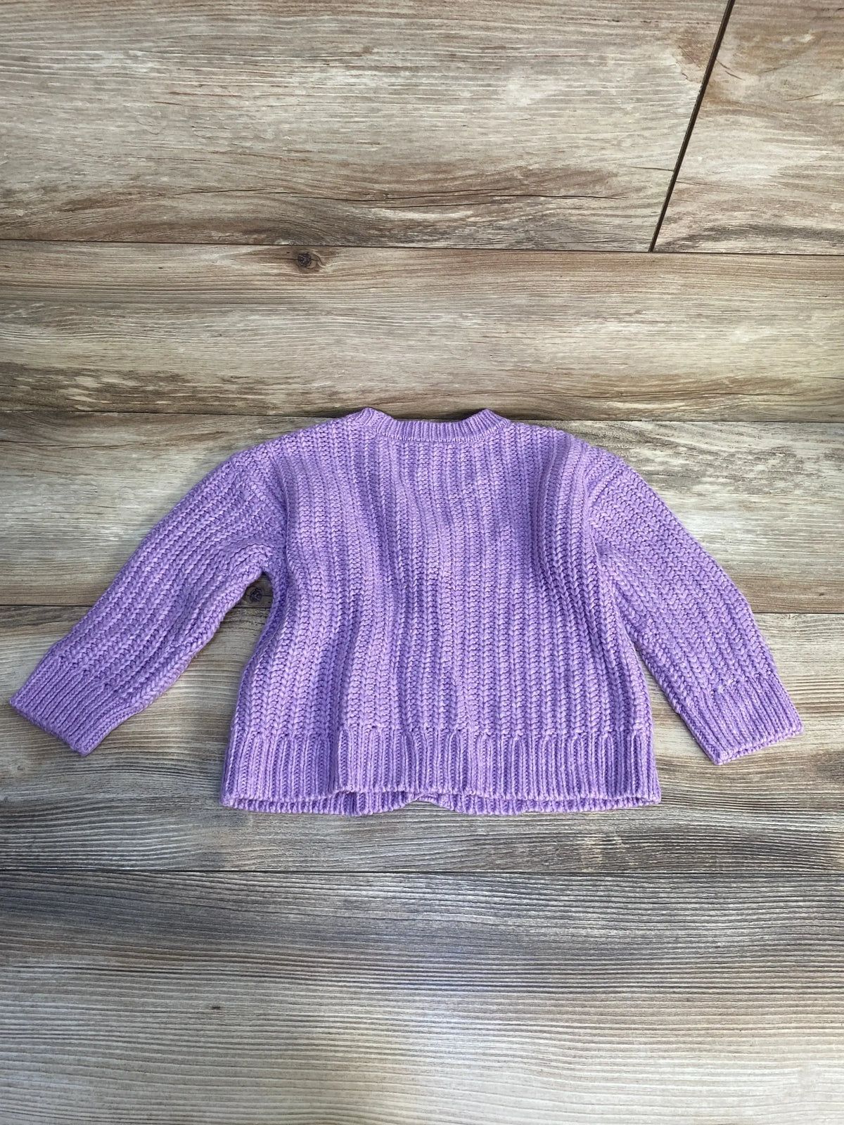 Back view of OshKosh lilac toddler cardigan size 18 months showcasing ribbed knit texture and long sleeves on a wooden background