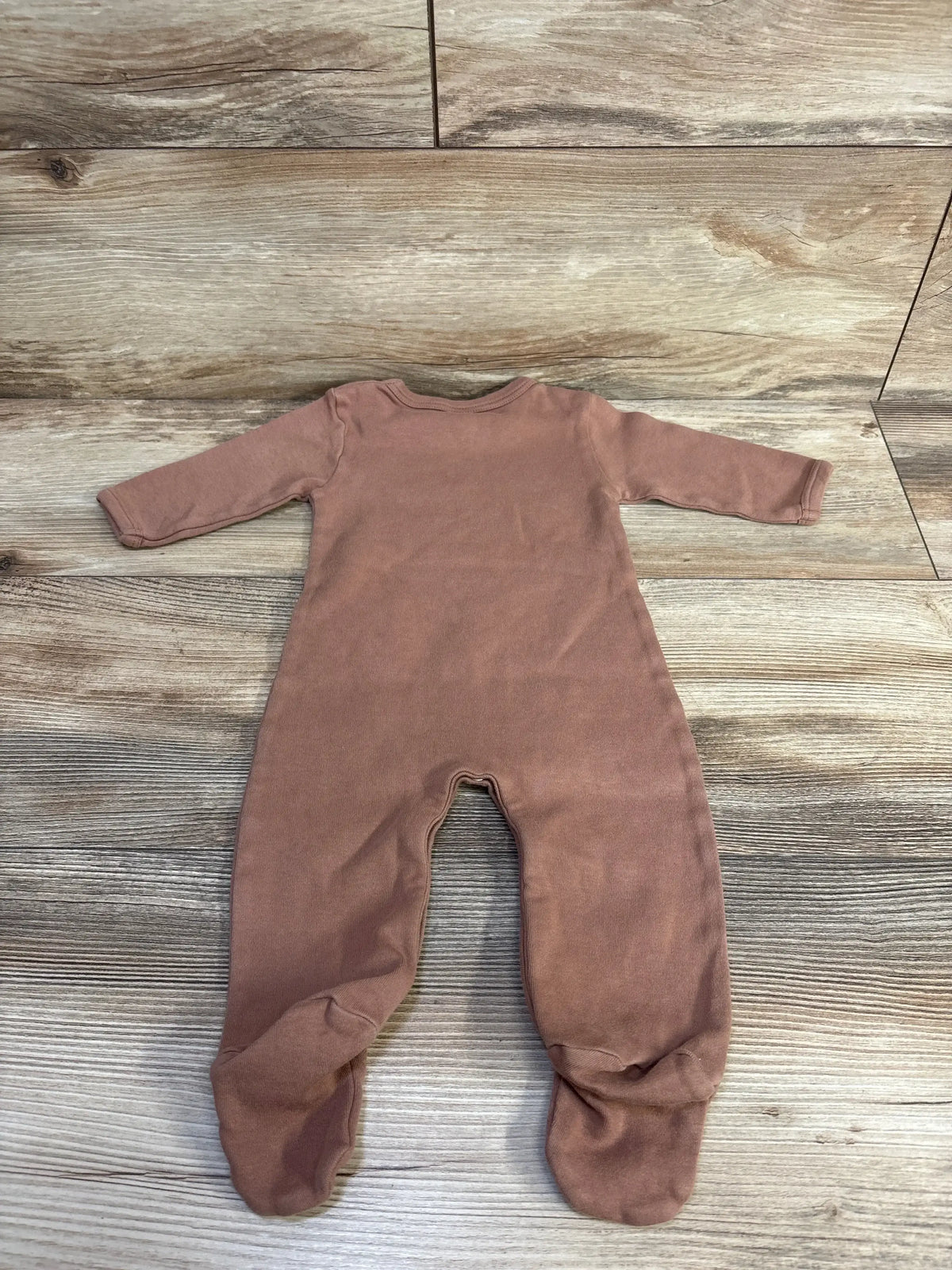 Flat lay of brown Kate Quinn footie coverall for 3-6 months showing long sleeves and enclosed feet on light wood floor