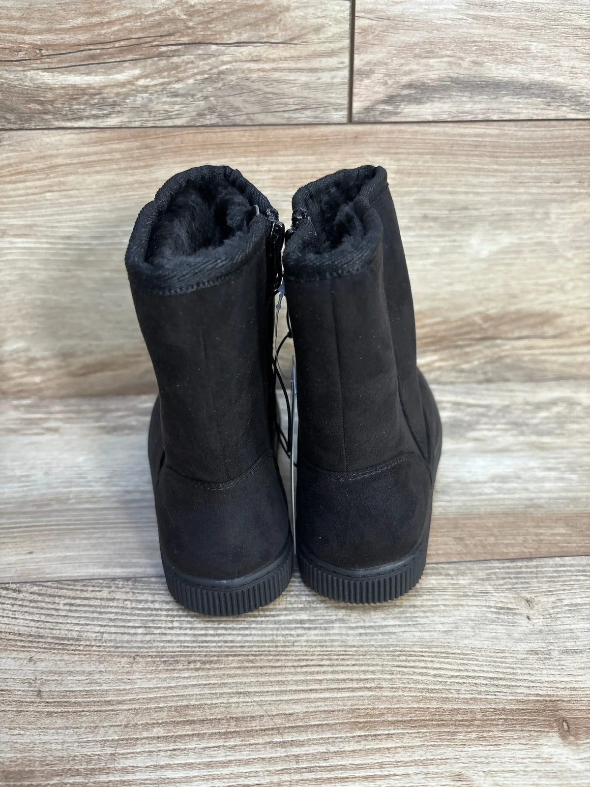 Rear view of Cat and Jack Pip shearling style kids boots with black faux fur lining and ribbed rubber soles on wood floor