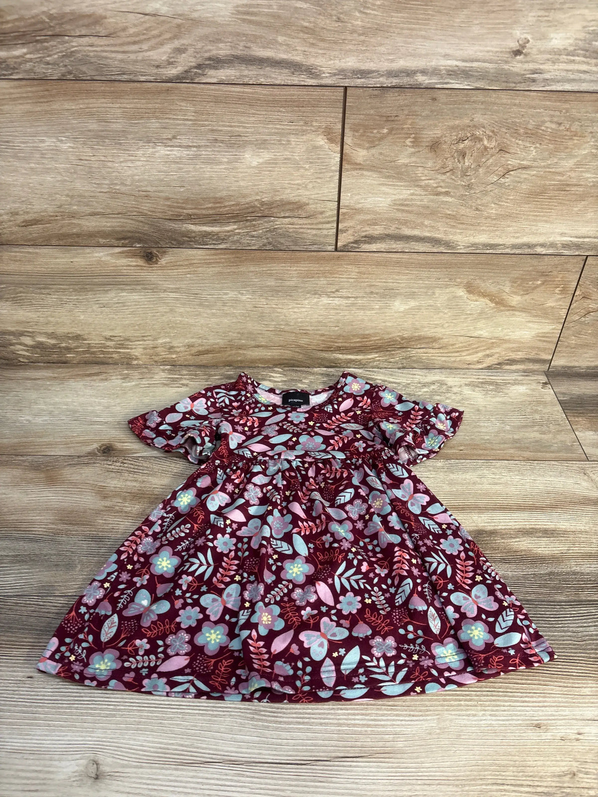 Front view of Picapino floral dress in maroon, size 12 months, showcasing delicate floral print and short sleeves on a wood-look floor