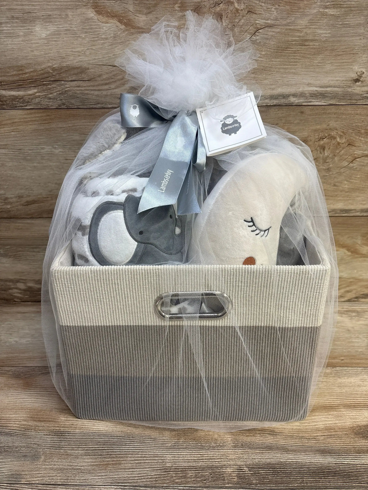 Front view of Lambs and Ivy gray 5-piece gift basket showing plush moon, gray elephant, blanket, and tulle bow on wood