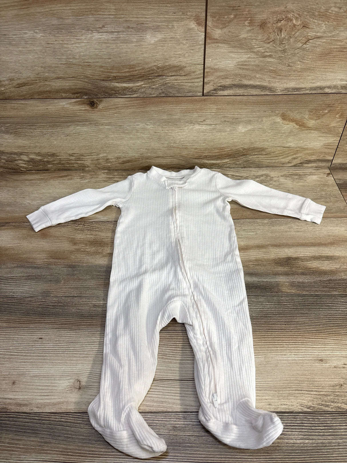 Front view of Carter's white ribbed footed sleeper size 9 months showing full-length front zipper and ribbed texture on wood floor
