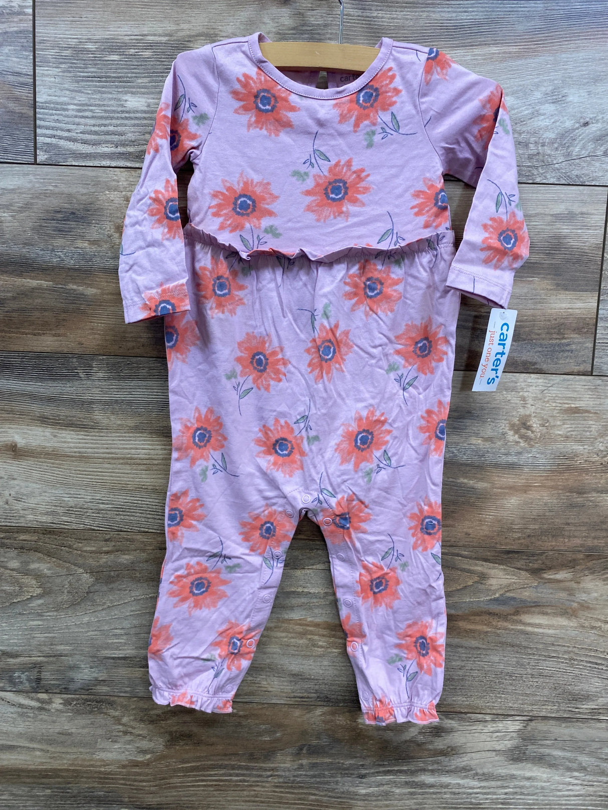 Carter's lilac baby romper with orange floral print and long sleeves on wooden floor