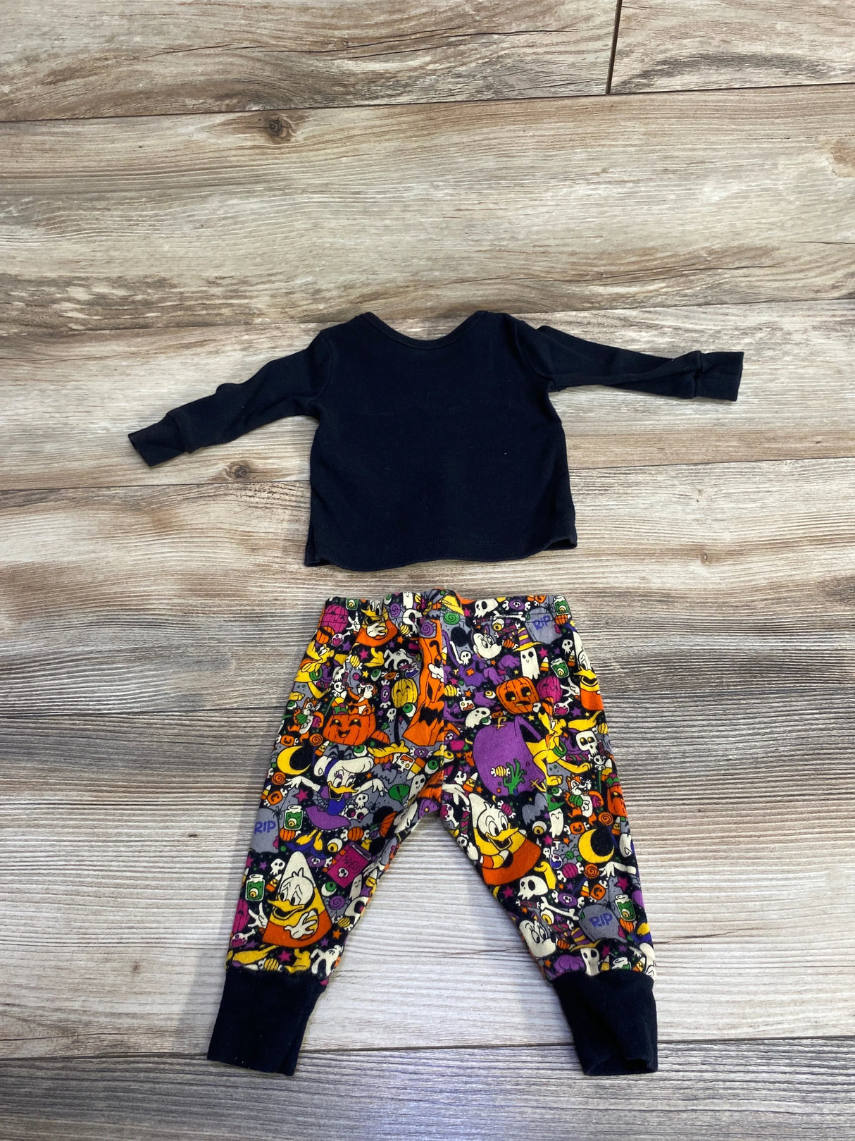 Kids Halloween pajama set with black long-sleeve top and colorful cartoon print pants featuring pumpkins, ghosts, and Disney characters.
