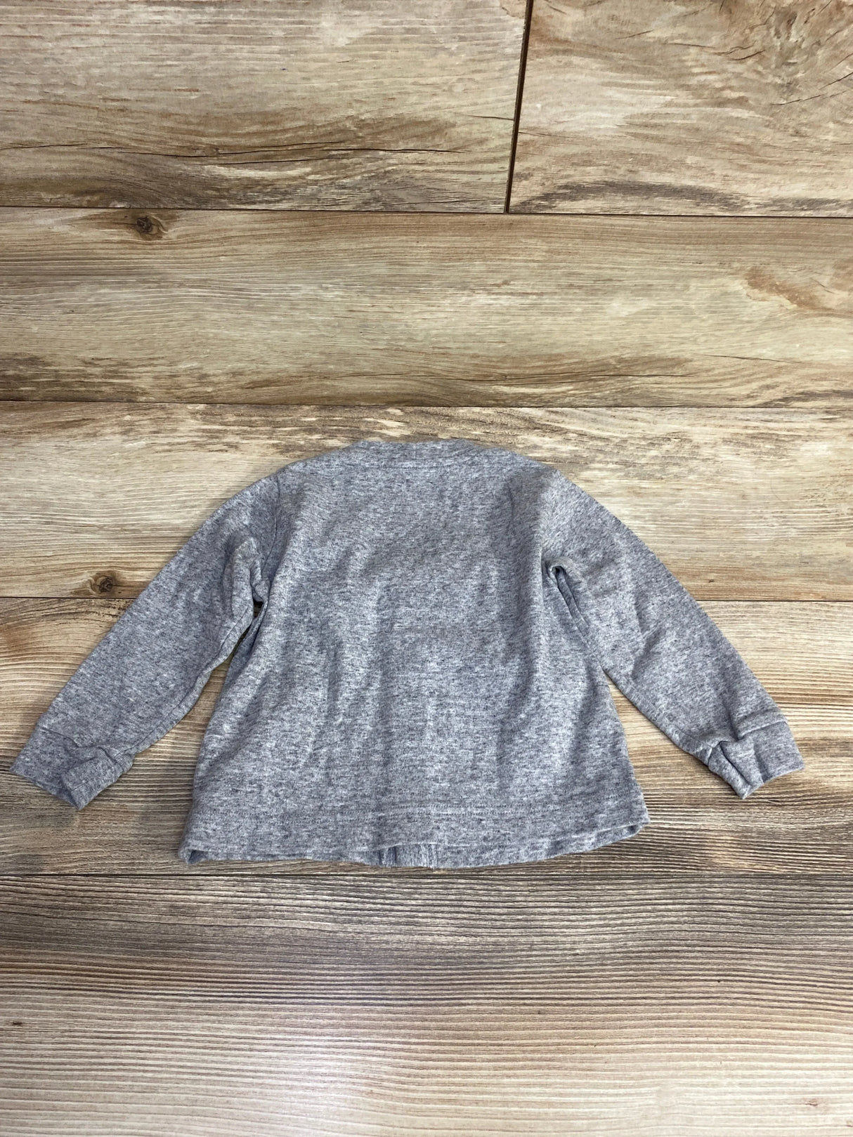 Back view of a gray long-sleeve shirt laid flat on wood plank background