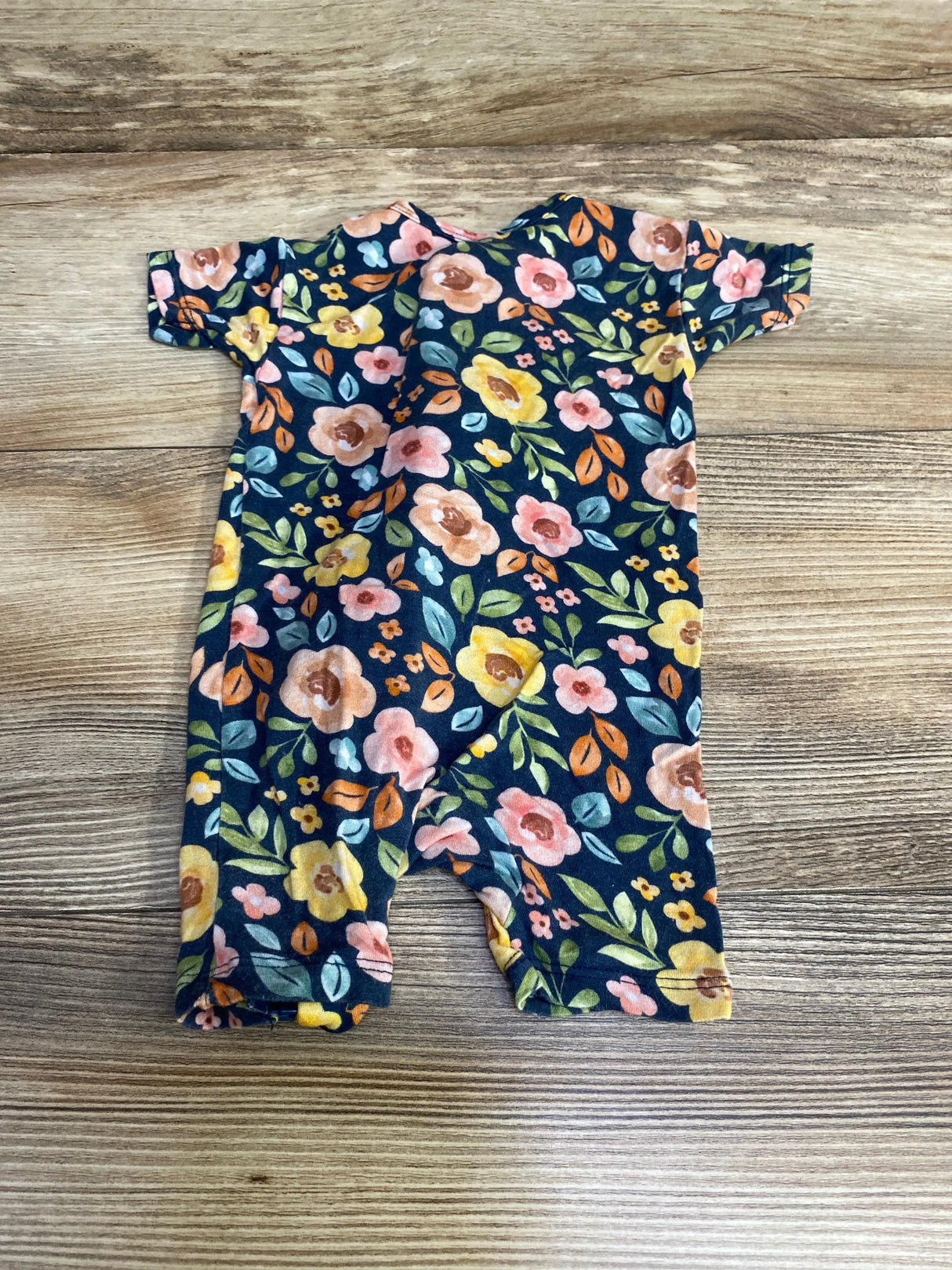 Flat-lay back view of Gerber newborn zip romper with navy floral print and short sleeves on wood background