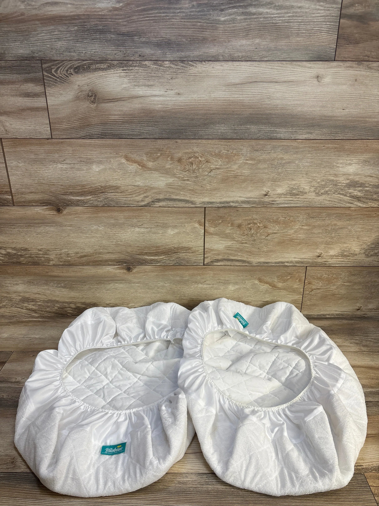 White quilted baby bassinet liners on wooden floor