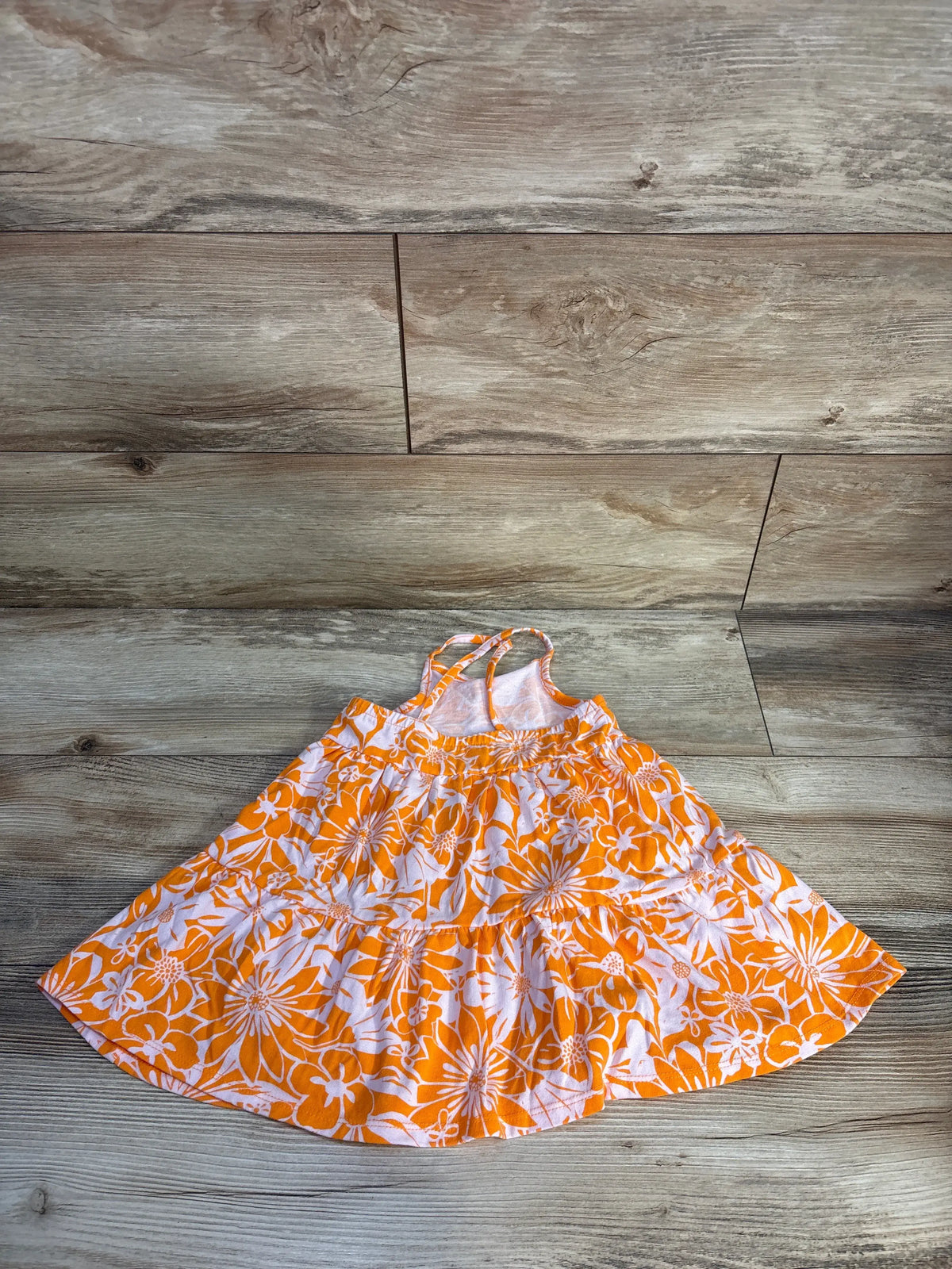Front view of Cat & Jack orange tank dress showcasing floral print and tiered skirt on wood plank background