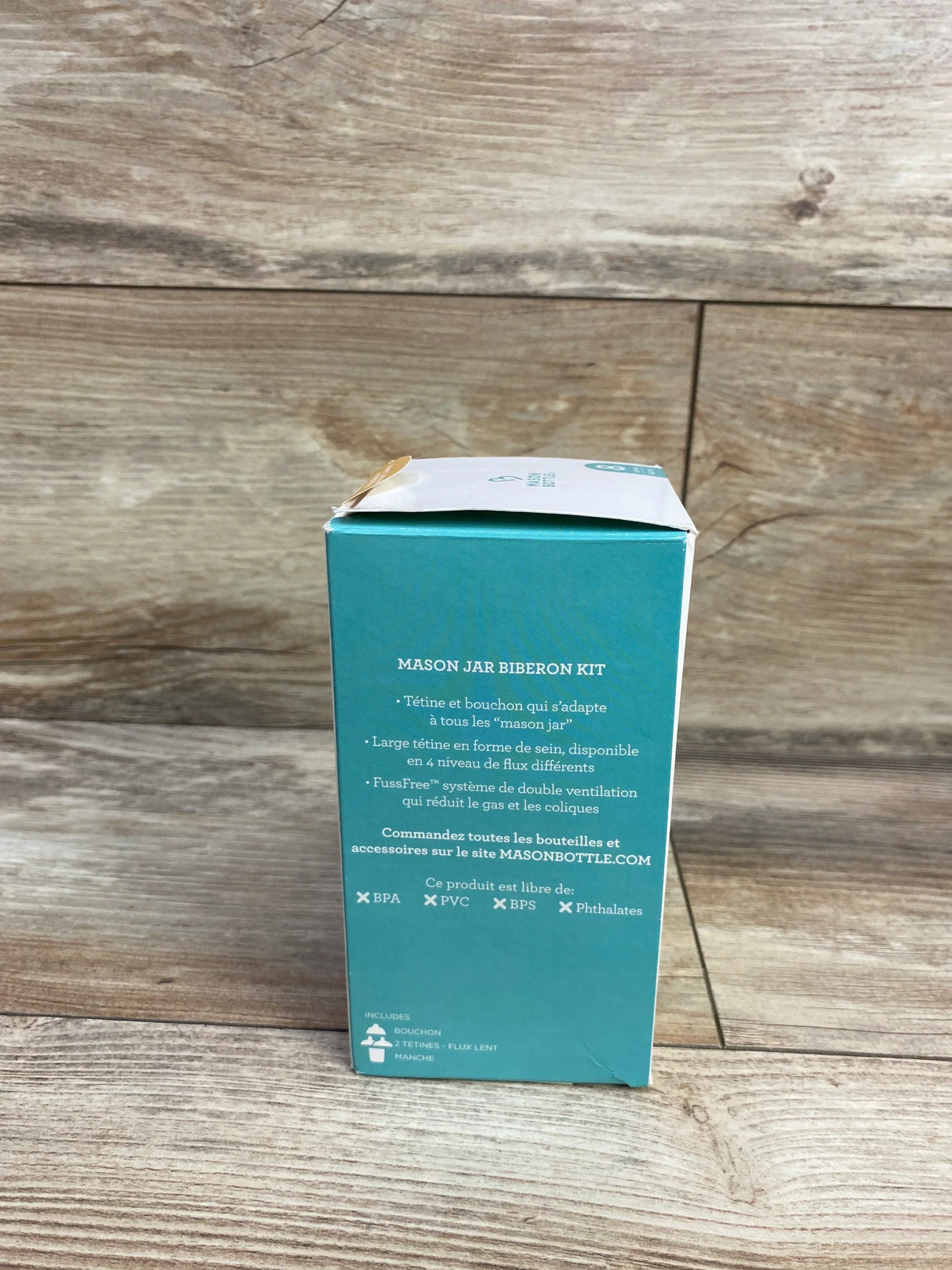 Mason jar baby bottle kit box with French product description against wood background