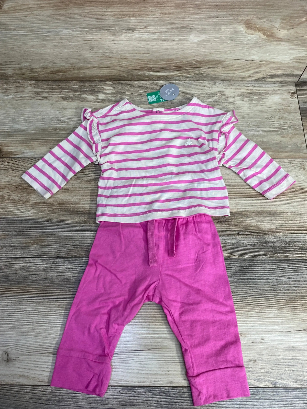 Baby girl's pink and white striped long sleeve top with ruffles and solid pink pants set on wooden floor