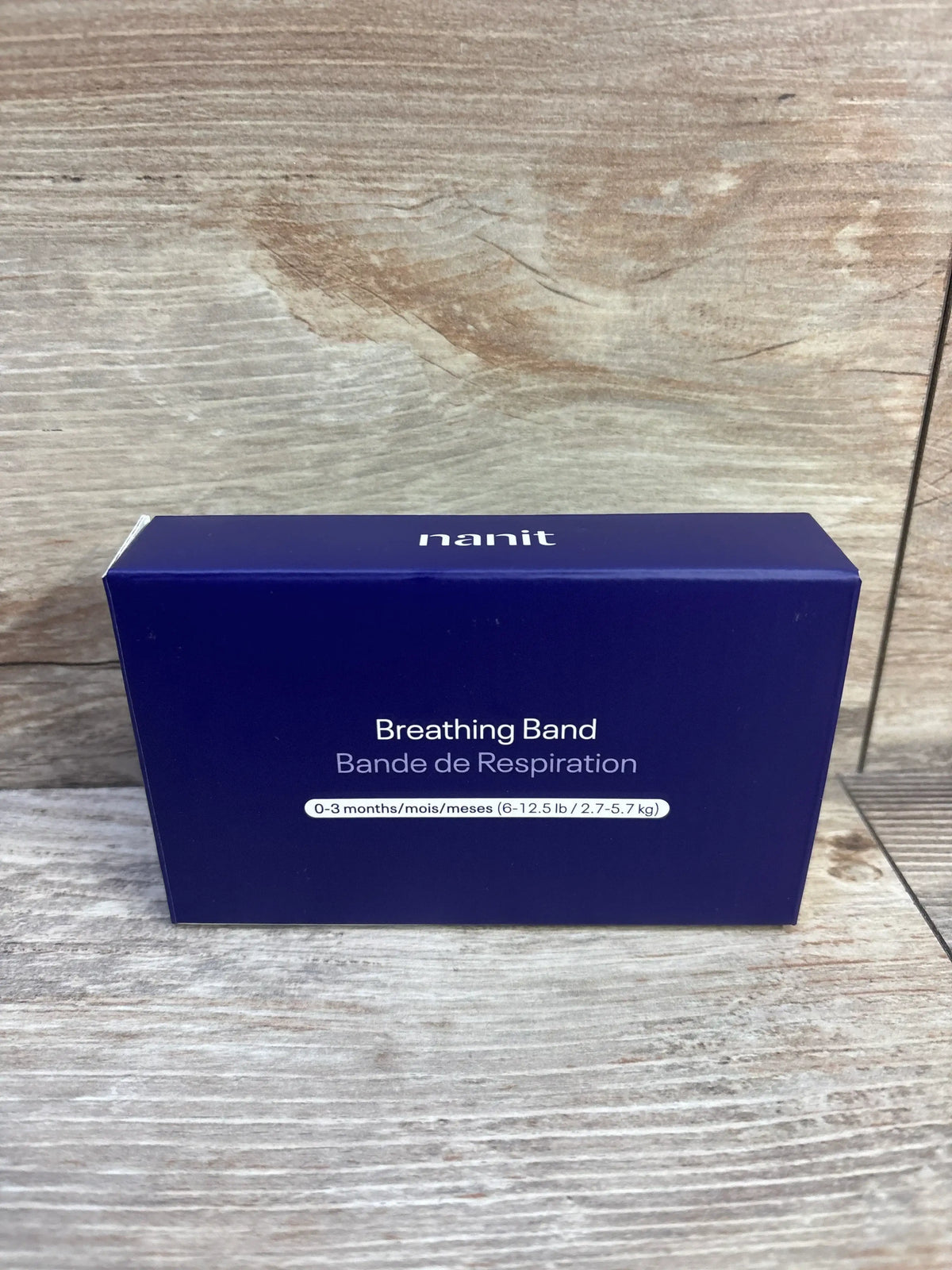 Front package view of NEW Nanit Breathing Band size 0-3m showcasing navy blue box labeled 6-12.5 lb on wood plank backdrop