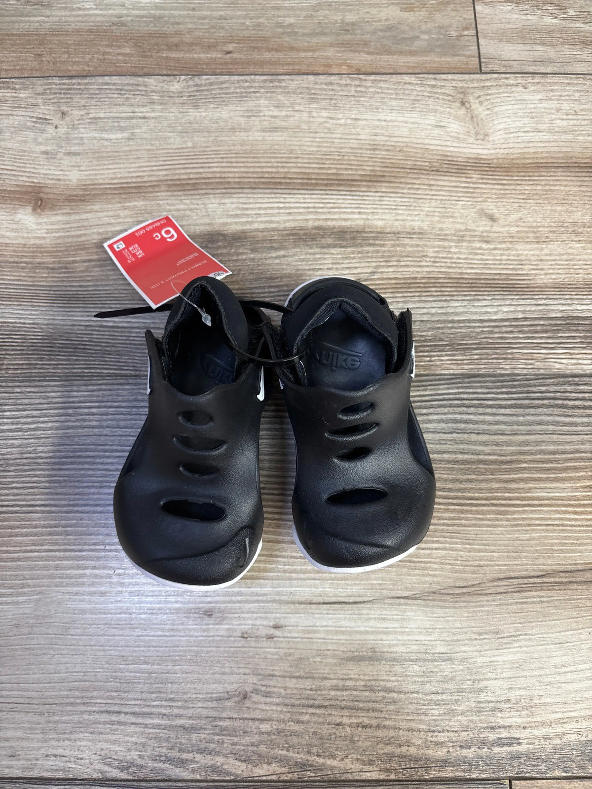 Front view of black Nike Sunray Protect 3 sandals, size 6C, with ventilation slots and adjustable straps on a wood-grain floor