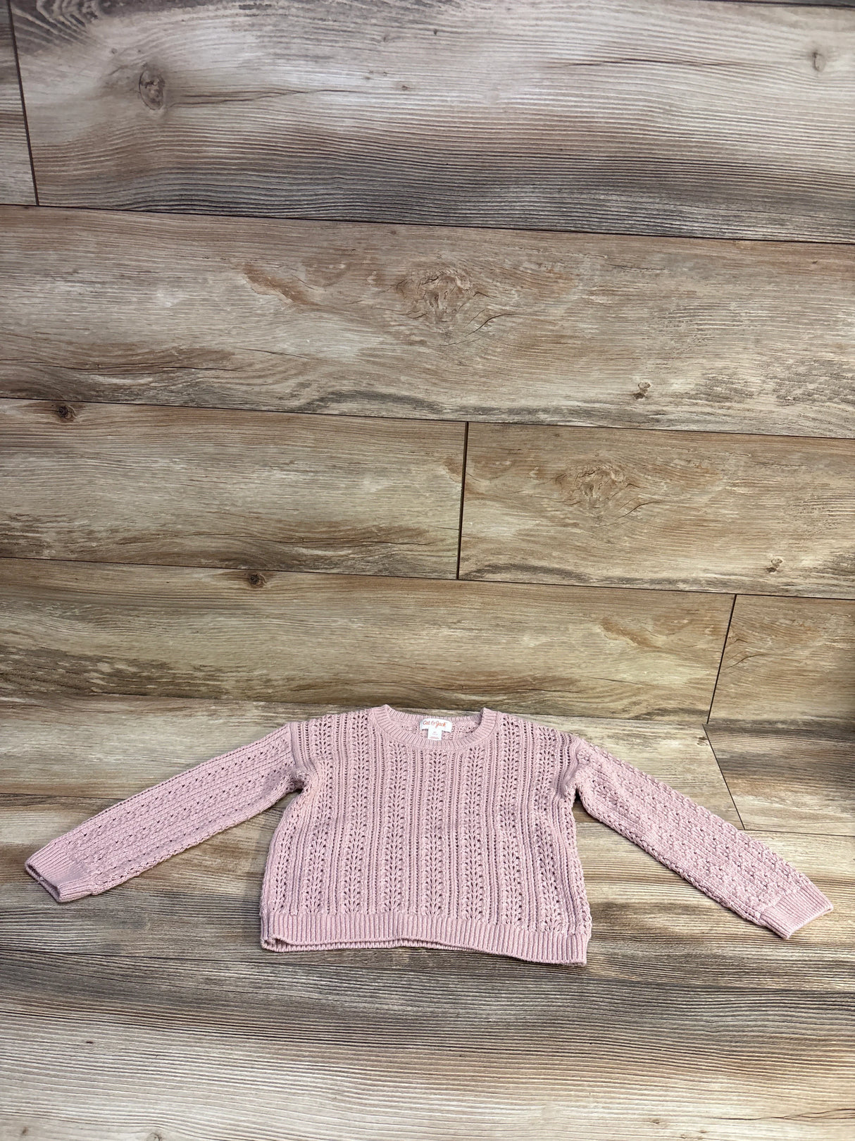 Flat lay of Cat & Jack pink knit toddler sweater (4T) showcasing openwork cable-knit pattern and crew neck with wood plank background