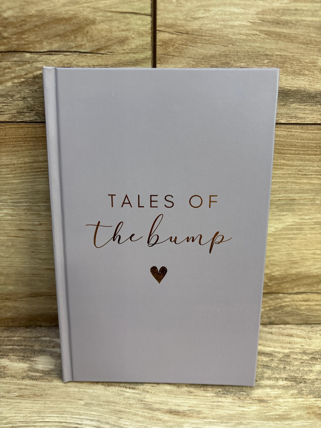 gray book titled Tales of the bump with a small heart on wooden surface