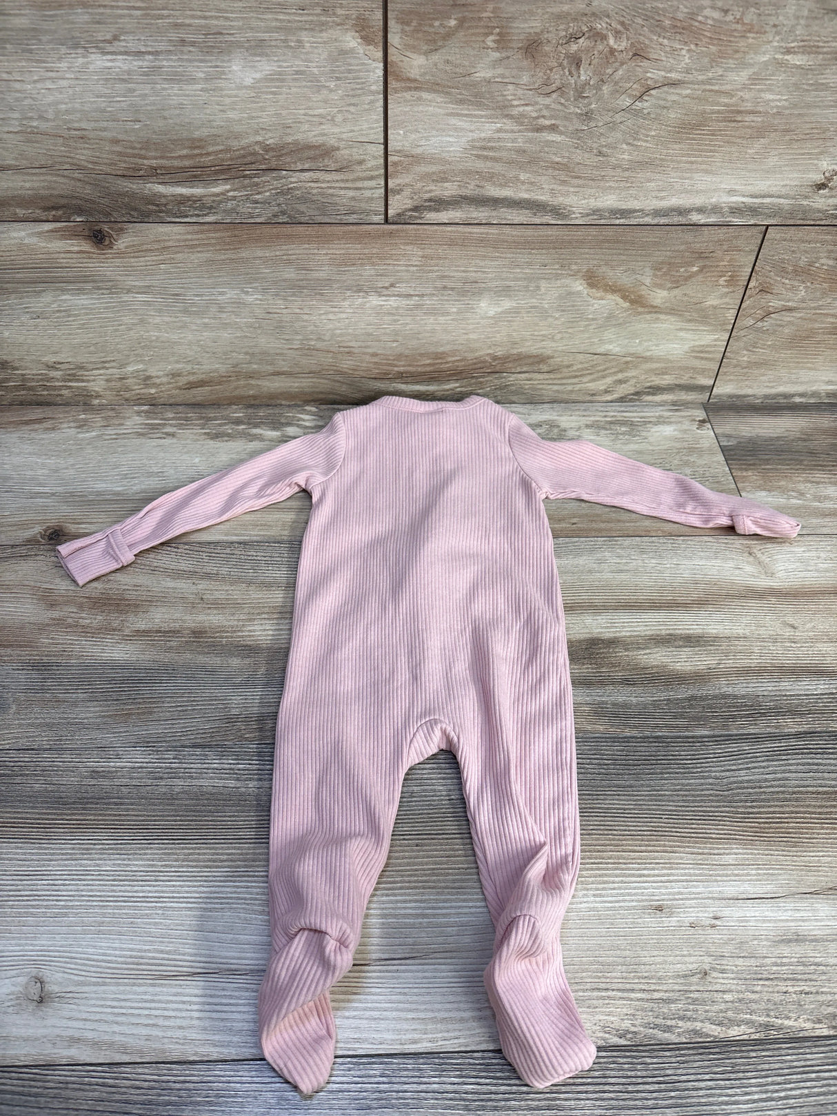 Back view of pink ribbed Old Navy footed sleeper size 3-6m showing long sleeves, fold-over cuffs on wood plank background