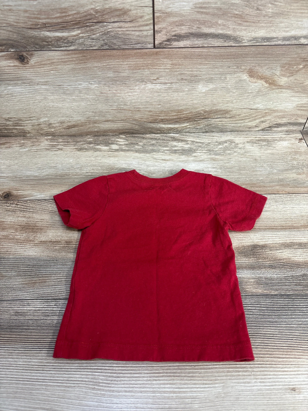 Red short sleeve toddler shirt on wooden background
