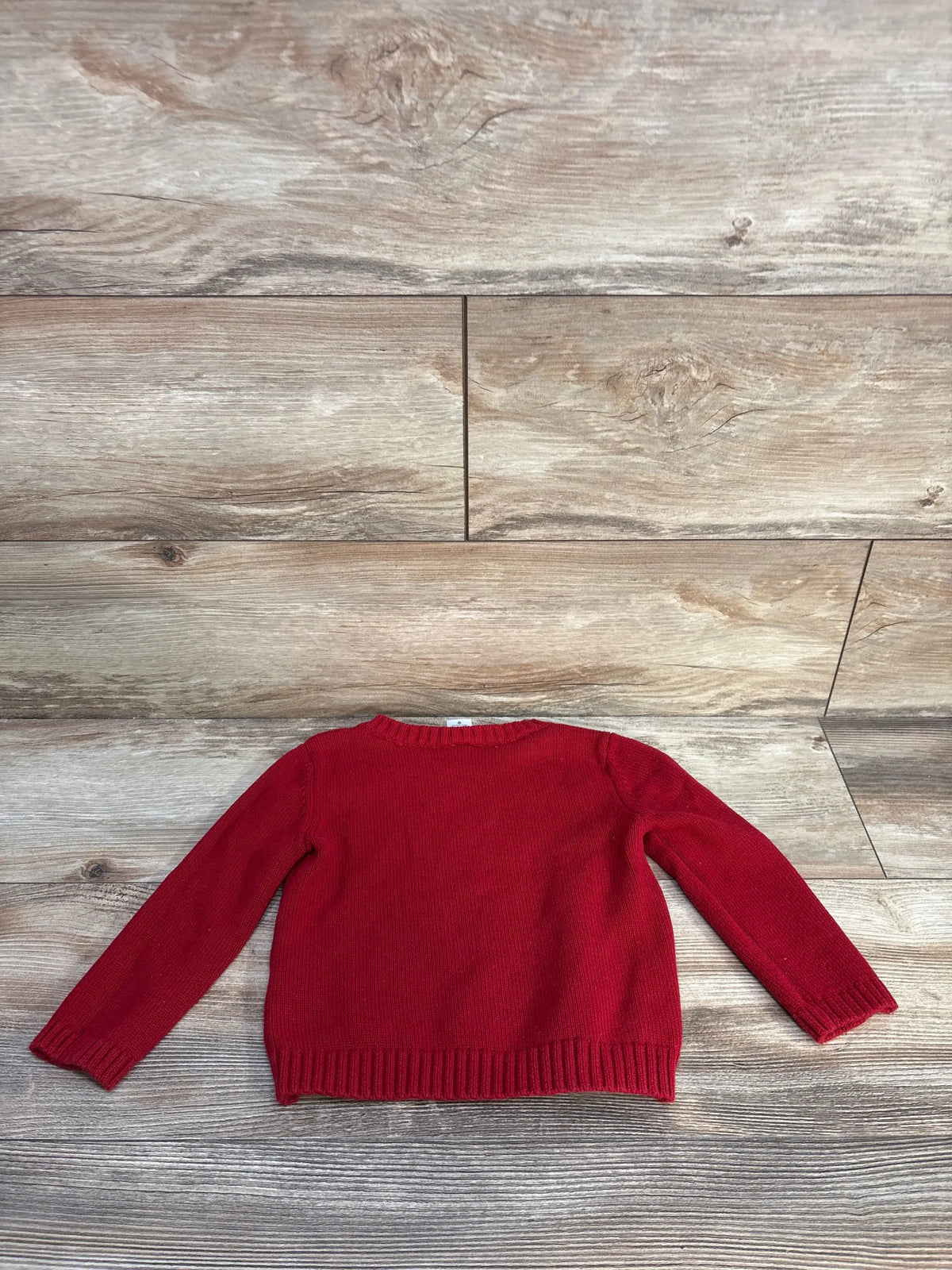 Front view of Carter’s red cable knit sweater showcasing long sleeves and ribbed trim on a wood background
