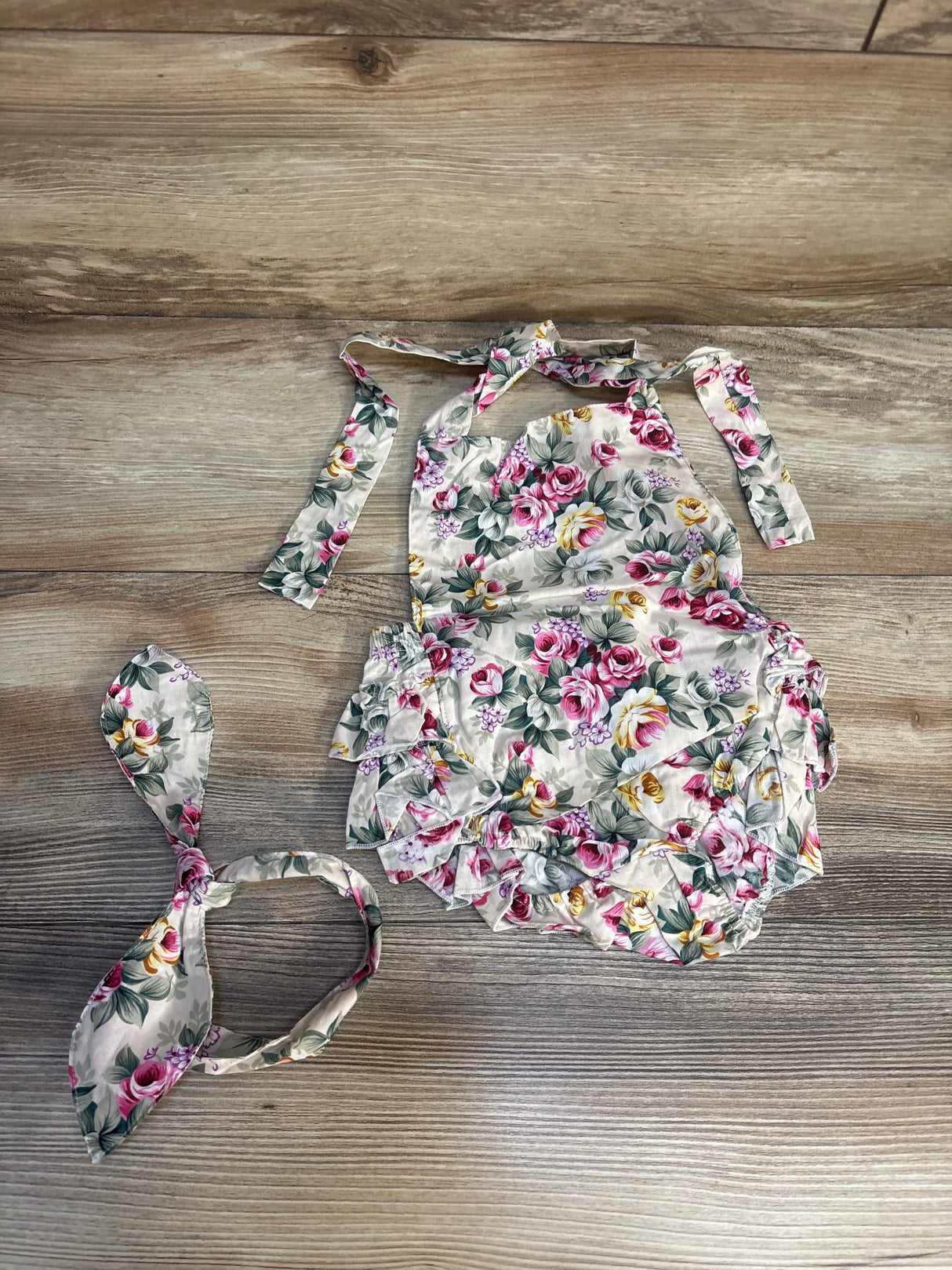 Floral baby romper and headband set with pink and yellow flowers on wood background
